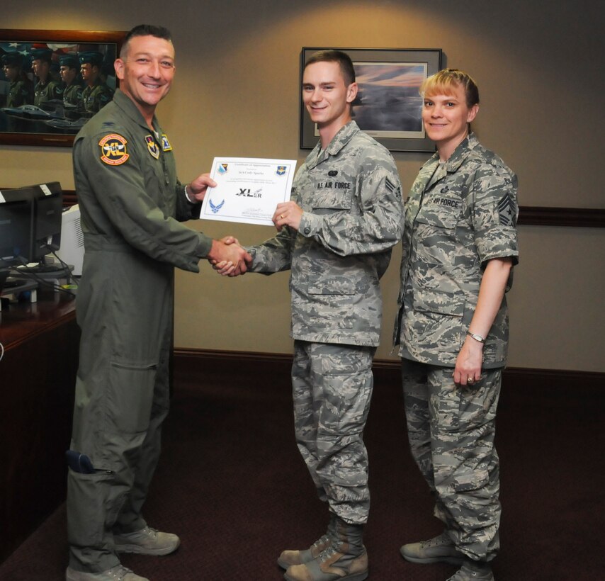 Senior Airman Cody Sparks, center, 47th Flying Training Wing knowledge operator, poses with Col. Brian Hastings, left, 47th FTW commander, and Chief Master Sgt. Teresa Clapper, right, 47th FTW command chief, after being presented the XLer of the week award here July 9, 2014. The XLer is a weekly award chosen by wing leadership and given to those who consistently make outstanding contributions to their unit and Laughlin. (U.S. Air Force photo by Airman 1st Class Jimmie D. Pike)(Released)