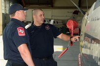 Tim Hagan, Joint Base San Antonio-Randolph firefighter, trains Ryan Edwards, City of San Antonio firefighter, during T-6 Texan II aircraft egress training July 09, 2014 at Joint Base San Antonio-Randolph. The firefighters received training on how to safely perform egress actions to ensure they know how to respond to any possible T-6 aircraft mishaps at the San Antonio International Airport. (U.S. Air Force photo by Johnny Saldivar)