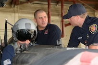 Jerry Knopf (left) and Tim Hagan (center), Joint Base San Antonio-Randolph firefighters, trains Ryan Edwards (right), City of San Antonio firefighter, during T-6 Texan II aircraft egress training July 09, 2014 at JBSA-Randolph. The firefighters received training on how to safely perform egress actions to ensure they know how to respond to any possible T-6 aircraft mishaps at the San Antonio International Airport. (U.S. Air Force photo by Johnny Saldivar)