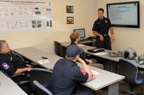 Jerry Knopf, Joint Base San Antonio-Randolph firefighter, briefs City of San Antonio firefighters, during T-6 Texan II aircraft egress training July 09, 2014 at JBSA-Randolph. The firefighters received training on how to safely perform egress actions to ensure they know how to respond to any possible T-6 aircraft mishaps at the San Antonio International Airport. (U.S. Air Force photo by Johnny Saldivar)