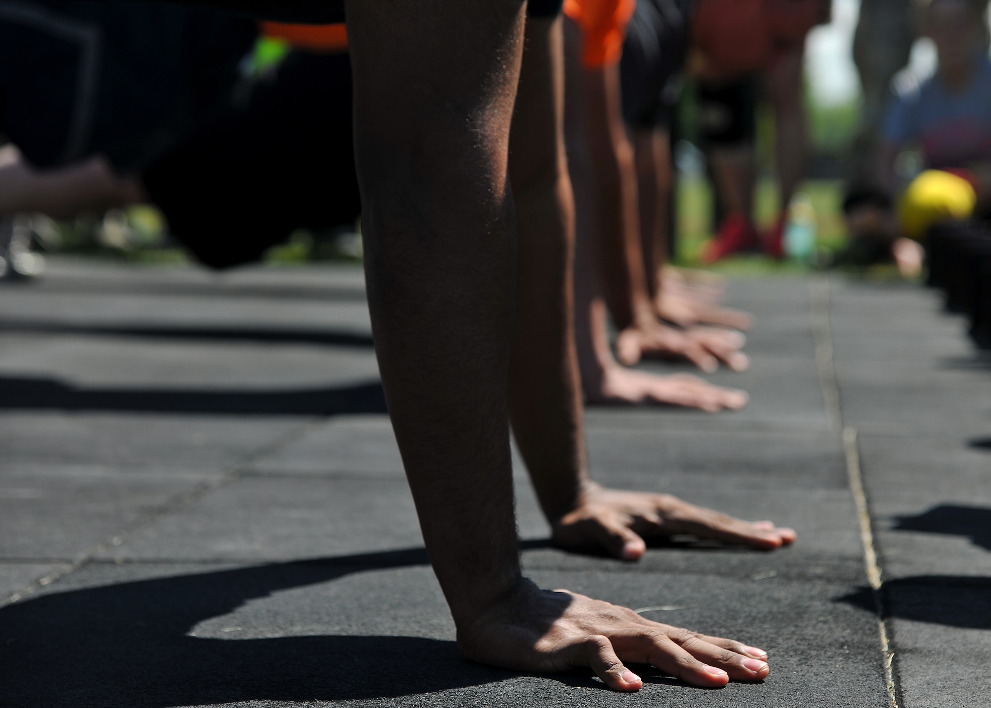 Members of the 319th Air Base Wing get into push-up position for one of three components of the Triple 8 Fitness Challenge on July 9, 2014, on Grand Forks Air Force Base, N.D. The Triple 8 Fitness Challenge is a premier fitness event designed to test the conditioning limits of Air Force athletes. The event challenges Airmen to run 1.5 miles in under nine minutes, as well as perform at least 80 push-ups and 80 sit-ups each in one minute or less. (U.S. Air Force photo/Senior Airman Xavier Navarro)