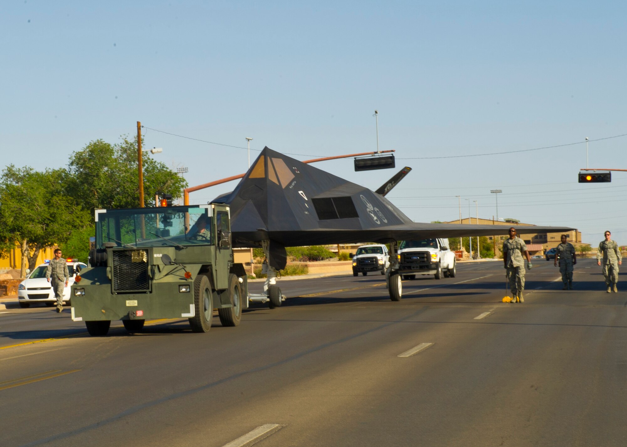Members of Team Holloman walk along side the F-117 Nighthawk down First Street at Holloman Air Force Base, N.M., June 28. The F-117 has been on static display in Holloman’s Heritage Airpark since its retirement in 2008. Due to sun and inclement weather damage, the 49th Maintenance Squadron removed and towed the aircraft to begin the restoration process. The aircraft received structural maintenance, and a fresh paint job before it was returned for display in Heritage Airpark. (U.S. Air Force photo by Airman 1st Class Leah Ferrante/Released)