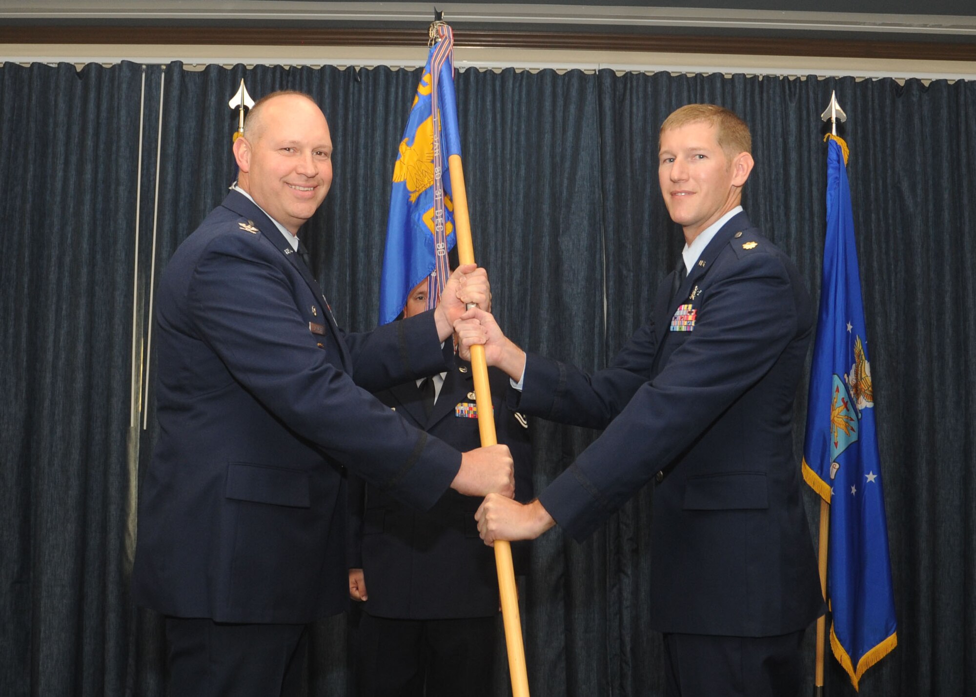 Col. Konrad Klausner passes the 92nd Communications Squadron guidon to Maj. Jason Mayne during a change of command ceremony at Fairchild Air Force Base, Washington, July 10, 2014. Klausner is the 92nd Mission Support Group commander and Mayne is the new 92nd CS commander. (U.S. Air Force photo by Airman 1st Class Sam Fogleman/Released)