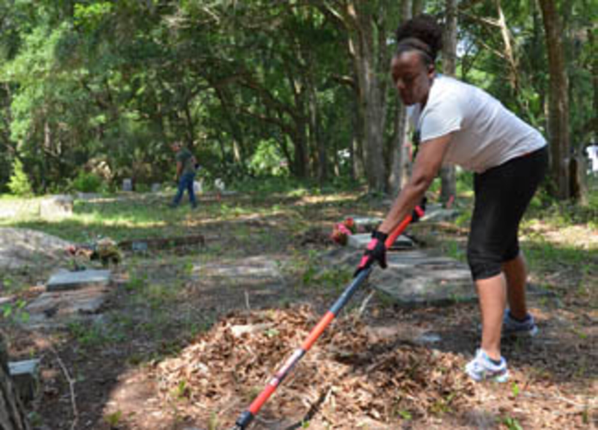 Master Sgt. Slychet Stone, 125th Fighter Wing Personnel Systems Manager, rakes leaves and branches from a cemetery plot during the Florida Air National Guard cleanup at the Pinehurst and San Sebastian Cemeteries in St. Augustine, Fla., May 24, 2014. Photo by Master Sgt. Thomas Kielbasa
