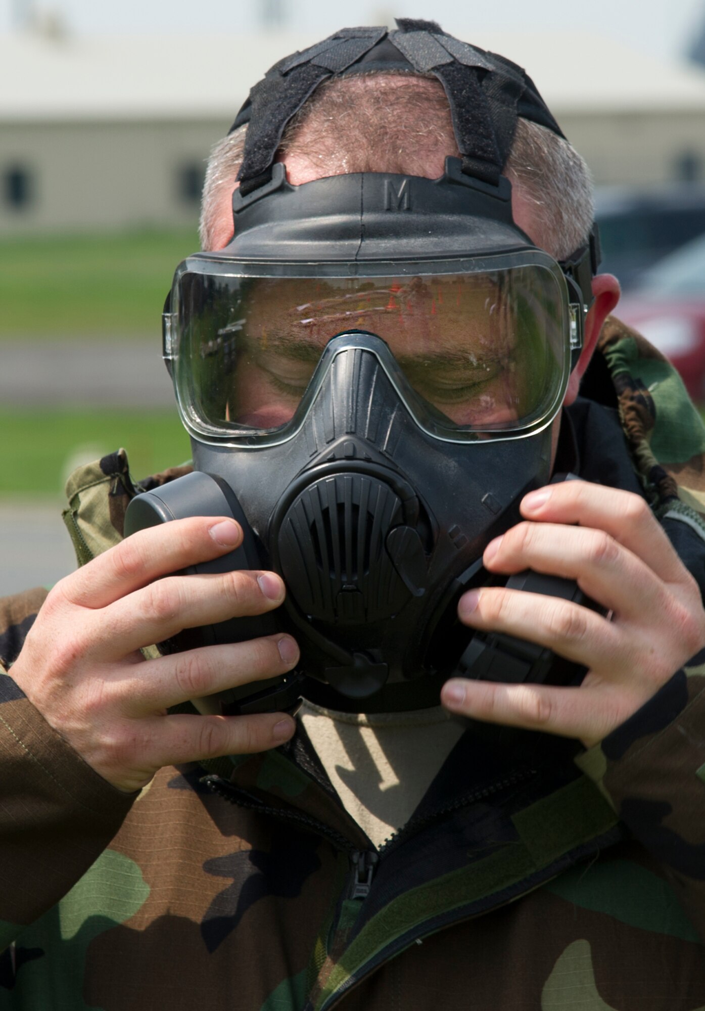 An Airman from the 5th Aircraft Maintenance Squadron adjusts his gas mask during an Ability to Survive and Operate Training course on Minot Air Force Base, N.D., July 8, 2014. Airmen participated in the course to refresh their training on the proper use of personal protective gear. (U.S. Air Force photo/Senior Airman Andrew Crawford)