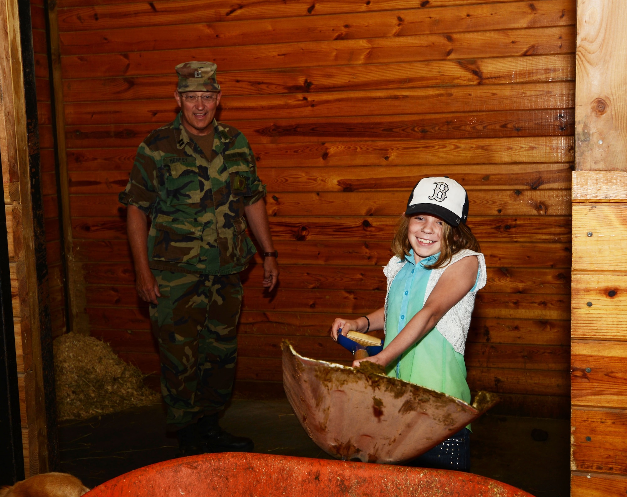 Gabriella Phillips, 9, mucks out a horse stall under the instruction of Capt. Edward Henfey, commanding officer of the 1st Company Governor's Horse Guard in Avon, Conn., June 21, 2014. Gabriella was participating in the Horses to Homecoming program, which includes teaching the children about barn duties while helping military children reconnect with their parents. (U.S. Air National Guard photo by Senior Airman Pierce)
