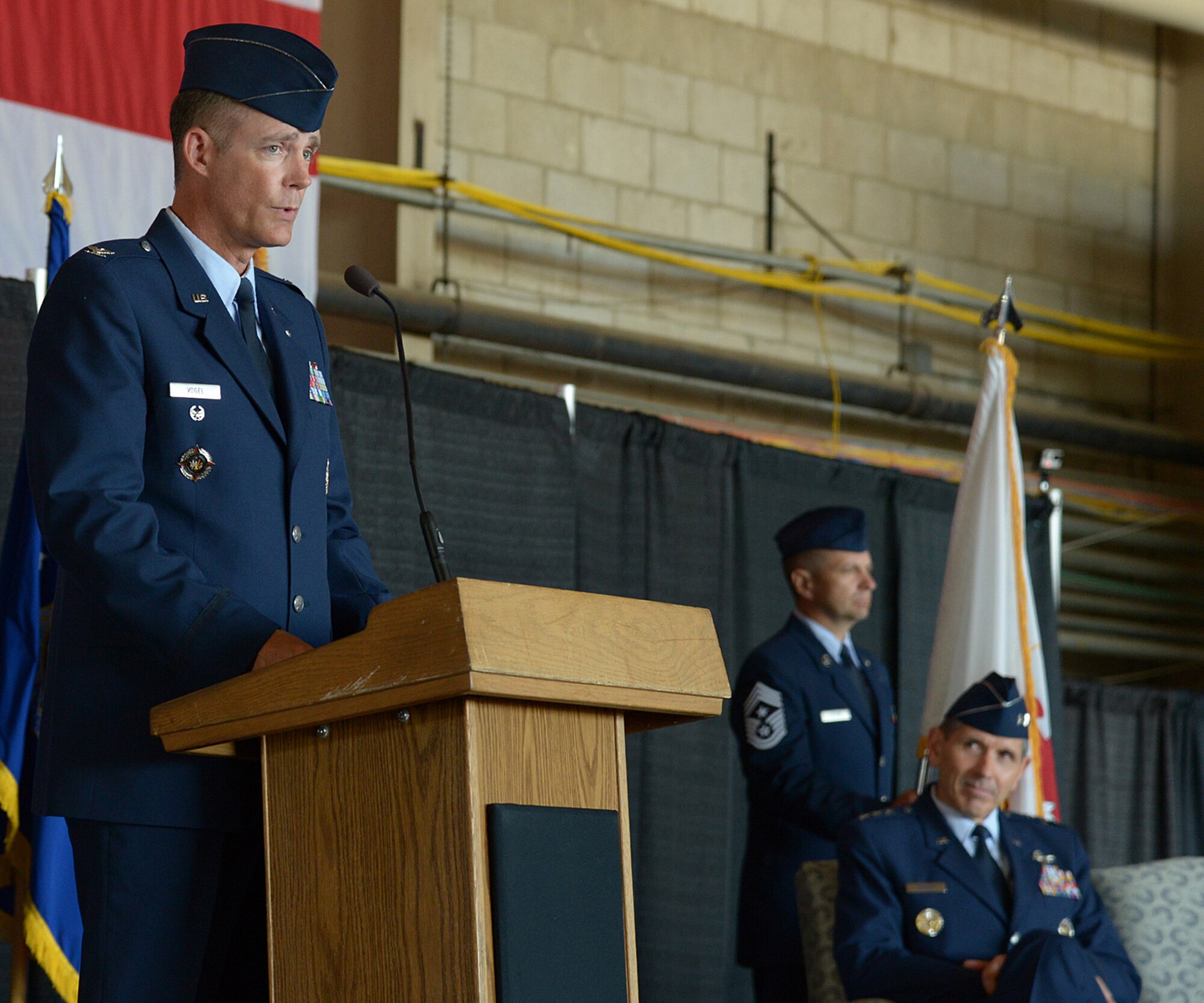 HANSCOM AIR FORCE BASE, Mass. – Col. Michael A. Vogel, new 66th Air Base Group commander, speaks to the audience during the 66th Air Base Group Change of Command ceremony at the Hanscom Aero Club Hangar July 10, while Lt. Gen. C. D. Moore II, Air Force Life Cycle Management Center commander, looks on. Vogel assumed command from Col. Lester A. Weilacher who is transferring to Langley Air Force Base. (U.S. Air Force photo by Walter Santos)   