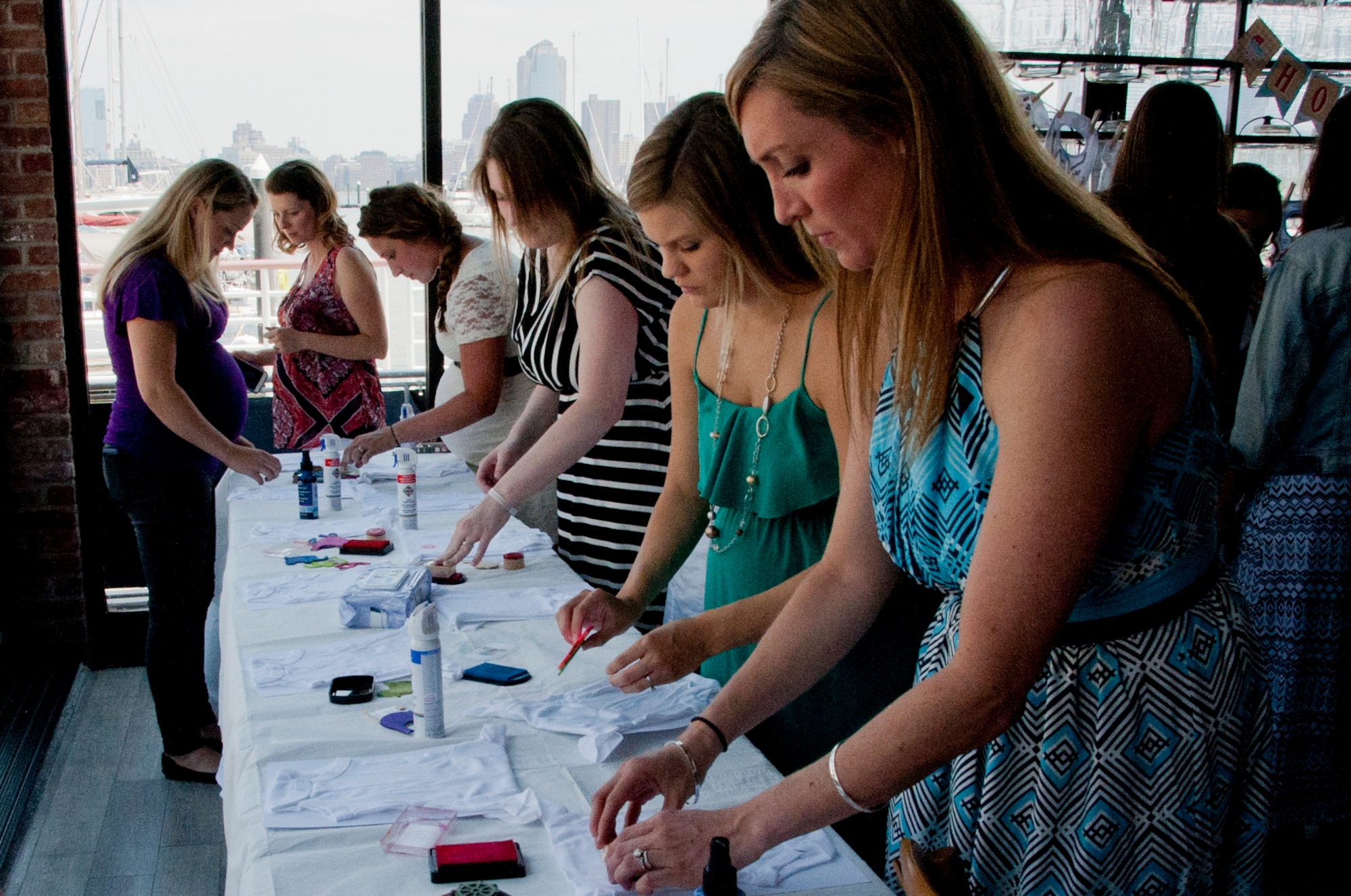Mothers from Joint Base McGuire-Dix-Lakehurst  decorate newborn onesies during an Operation Shower event in Jersey City, N.J. Operation Shower is a non-profit organization providing baby showers for military families across the country to ease the stress of having a new baby. (U.S. Air Force photo by Airman 1st Class Tara A. Williamson/Released)