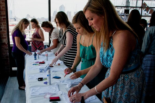 Mothers from Joint Base McGuire-Dix-Lakehurst decorate newborn onesies during an Operation Shower event in Jersey City, New Jersey. Operation Shower is a non-profit organization providing baby showers for military families across the country to ease the stress of having a new baby. (U.S. Air Force photo/Airman 1st Class Tara A. Williamson)