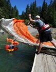 Tech. Sgt. Jeryd Leuck, 9th Operations Support Squadron Survival, Evasion, Resistance, and Escape specialist, throws a parachute over a U-2 pilot as part of water survival training July 3, 2014, at a lake in Nevada City, Calif. The U-2 pilots tested their ability to escape the canopy of a parachute after a simulated water landing. (U.S. Air Force photo by Airman 1st Class Ramon A. Adelan/ Released) 