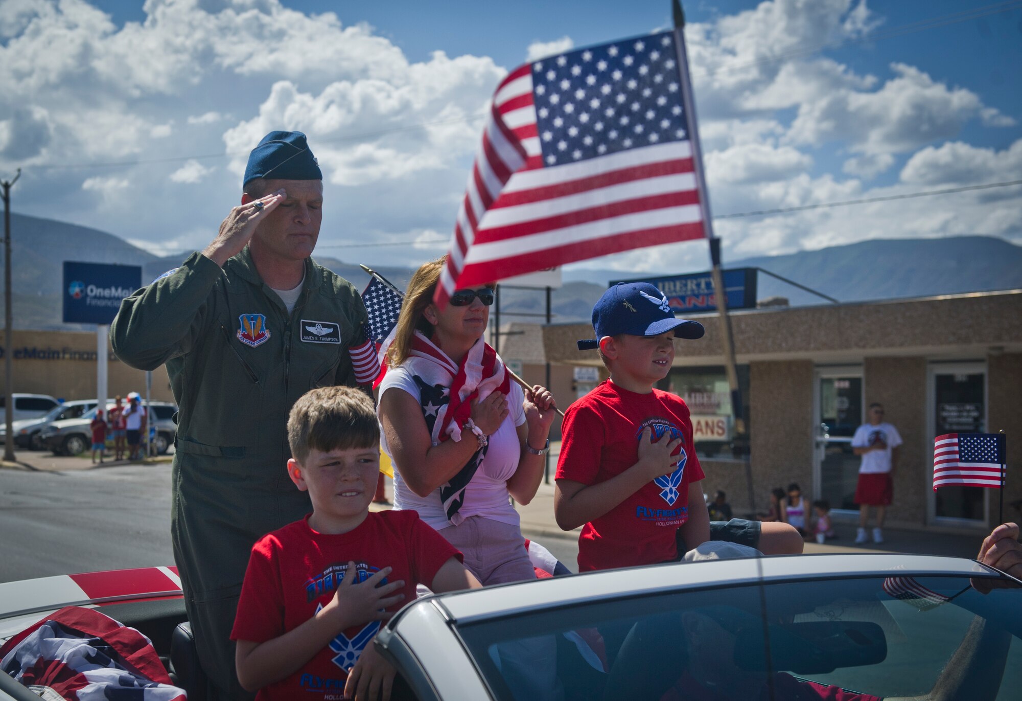 Honored guests, 49th Fighter Wing commander Col. James Thompson and his family show respect during the city of Alamogordo, N.M., 4th of July parade. Members of the base join with the local community to celebrate Independence Day. (U.S. Air Force photo by Airman1st Class Chase Cannon/Released)