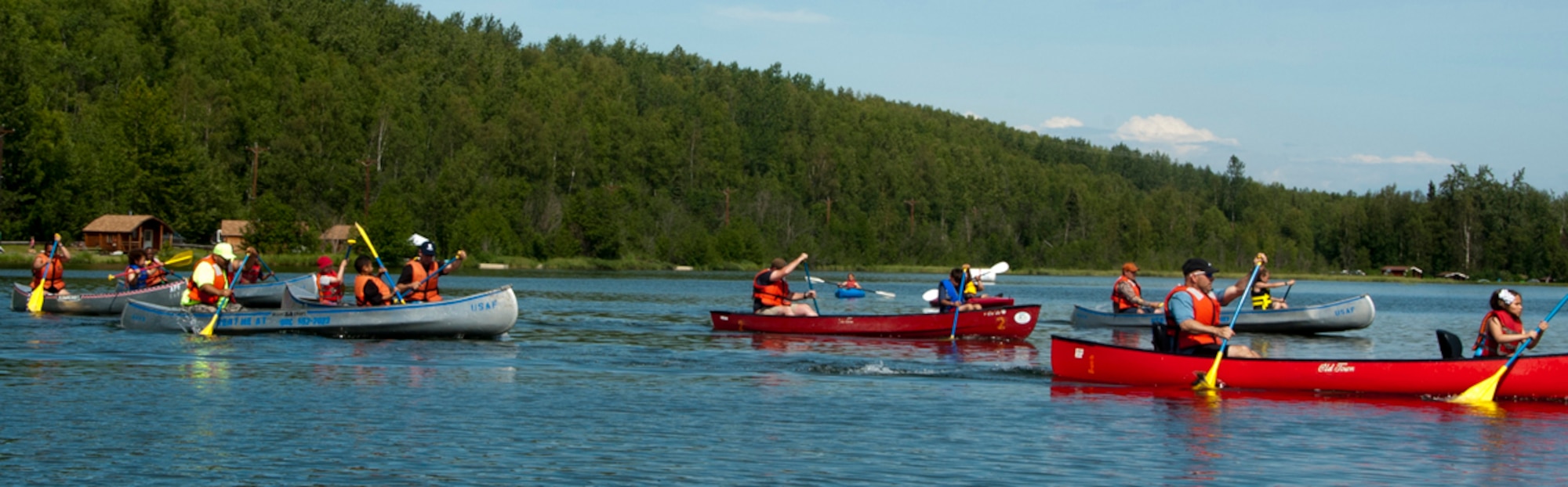 Military members and their families race canoes during the second annual Otter Fest on Joint Base Elmendorf-Richardson, Alaska, July 5, 2014. The race started and ended at the dock on Otter Lake and consisted of two-man teams. (U.S. Air Force photo/Airman 1st Class Tammie Ramsouer)