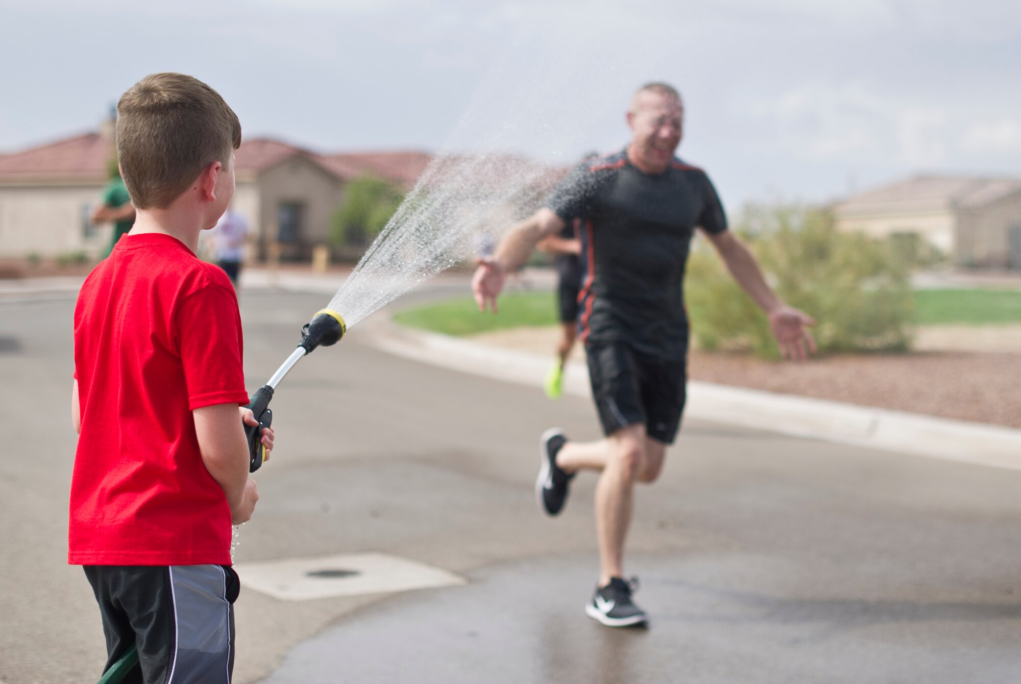 A child sprays a race participant during the water fun run at Freedom Fest Independence Day celebration at Holloman Air Force Base, N.M., July 3. Freedom Fest took place in the Domenici Fitness and Sports Center parking lot and included carnival games, rides, and live music for Airmen and their families. (U.S. Air Force photo by Airman 1st Class Aaron Montoya/Released)