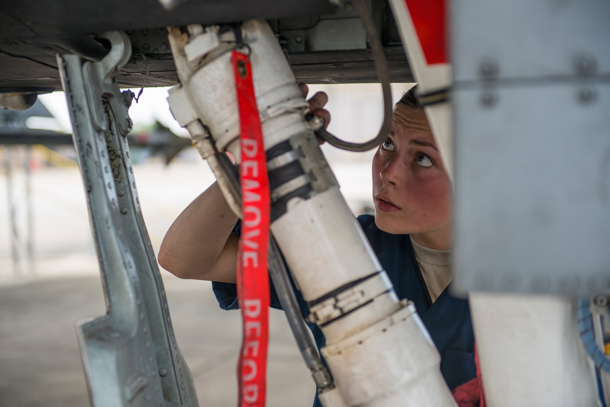 U.S. Air Force Airman 1st Class Robin Burke, 23d Aircraft Maintenance Squadron dedicated crew chief, inspects the bottom of an A-10C Thunderbolt II at Moody Air Force Base, Ga., July 9, 2014. As part of this post-flight inspection, Burke searched for cracked, missing or loose parts and ensured necessary servicing had been completed. (U.S. Air Force photo by Airman 1st Class Ryan Callaghan/Released)