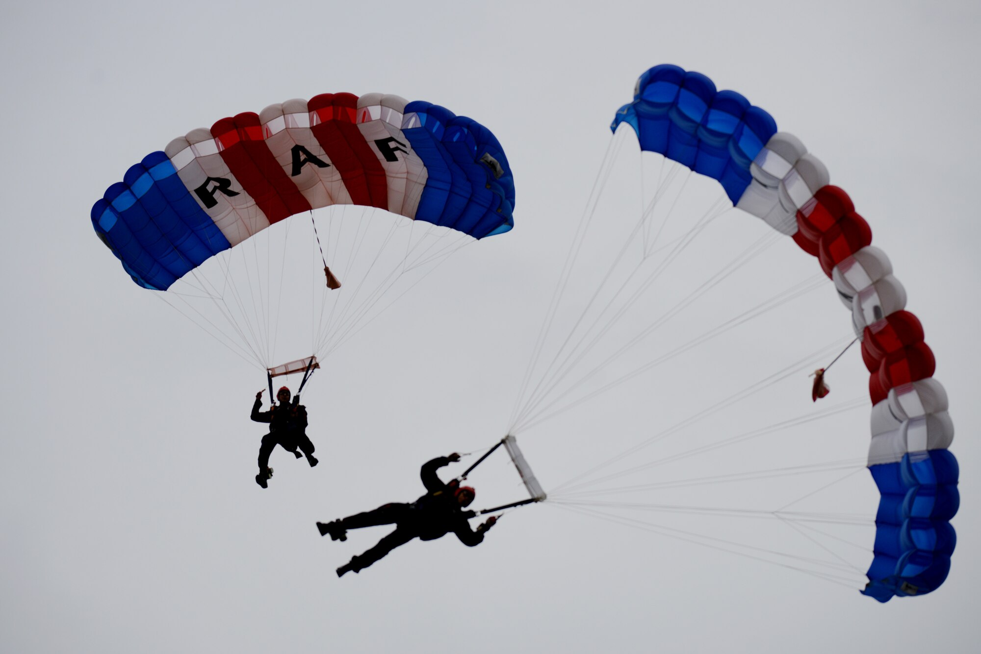 Members of the RAF Falcons, the United Kingdom’s premier military parachute display team, glide toward the ground during a Fourth of July festival at RAF Croughton, U.K., July 3, 2014. The RAF Falcons rely on a very specialized range of equipment, from parachutes to smoke generators, to carry out displays. (U.S. Air Force photo by Tech. Sgt. Chrissy Best/Released)