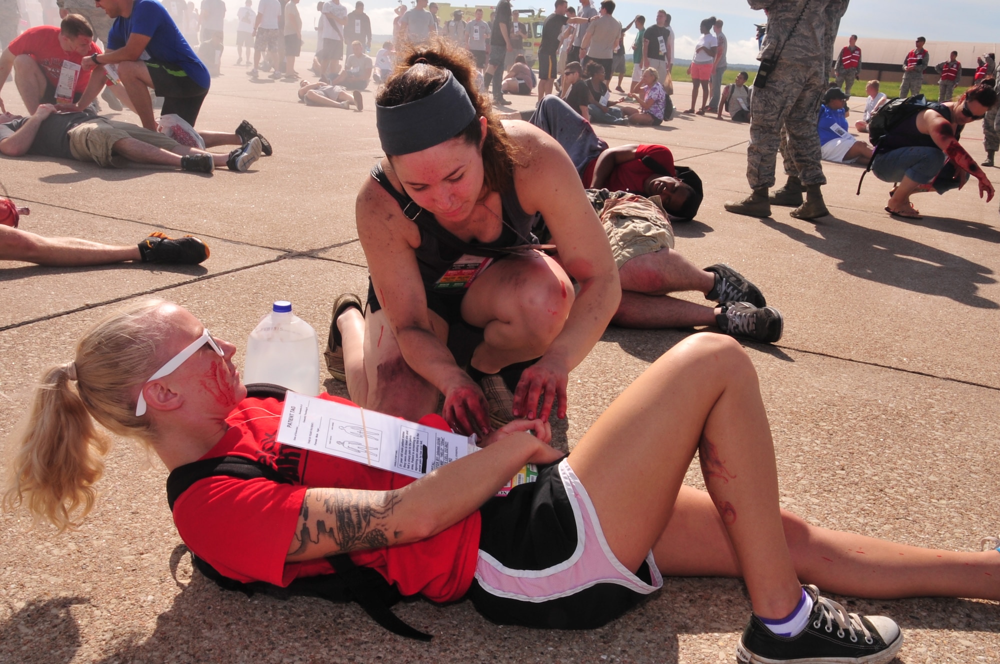 Senior Airman Corrine Hoffschneider, 55th Operations Support Squadron, gives aid to U.S. Air Force Staff Sgt. Samantha Nonnenmann, 2d Weather Squadron, during a mock emergency on the flight line at Offutt Air Force Base, Nebraska, June 28. This exercise was part of the annual Major Accident Response Exercise that is conducted to prepare first responders and leaders from Offutt and the surrounding communities in case of a major incident during the air show. (U.S. Air Force photo by D.P. Heard/Released)