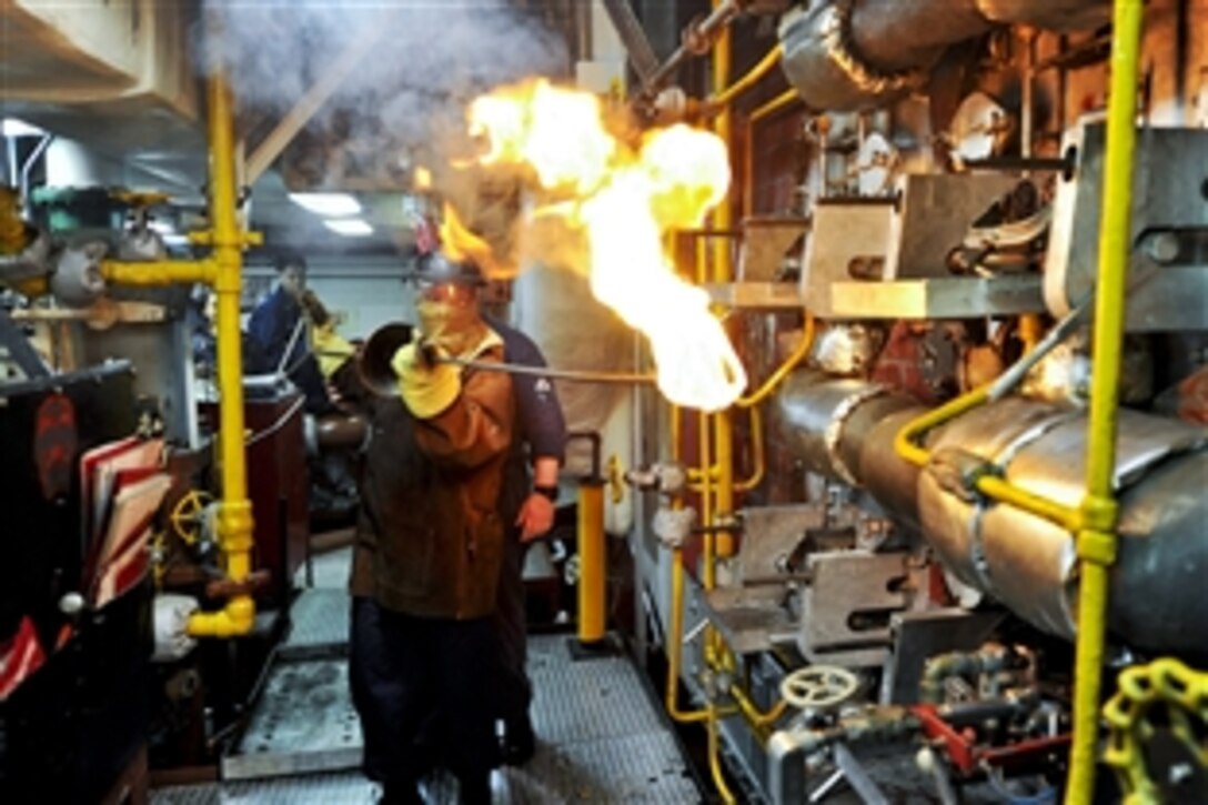U.S. Navy Petty Officer 2nd Class Siara Rodriguez lights off the boiler with assistance from Petty Officer 1st Class Jason Cockrum on the multipurpose amphibious assault ship USS Bataan in the U.S. 5th fleet area of responsibility, July 10, 2014. The Bataan is operating in the U.S. 6th Fleet area of responsibility to augment U.S. crisis response forces in the region. 