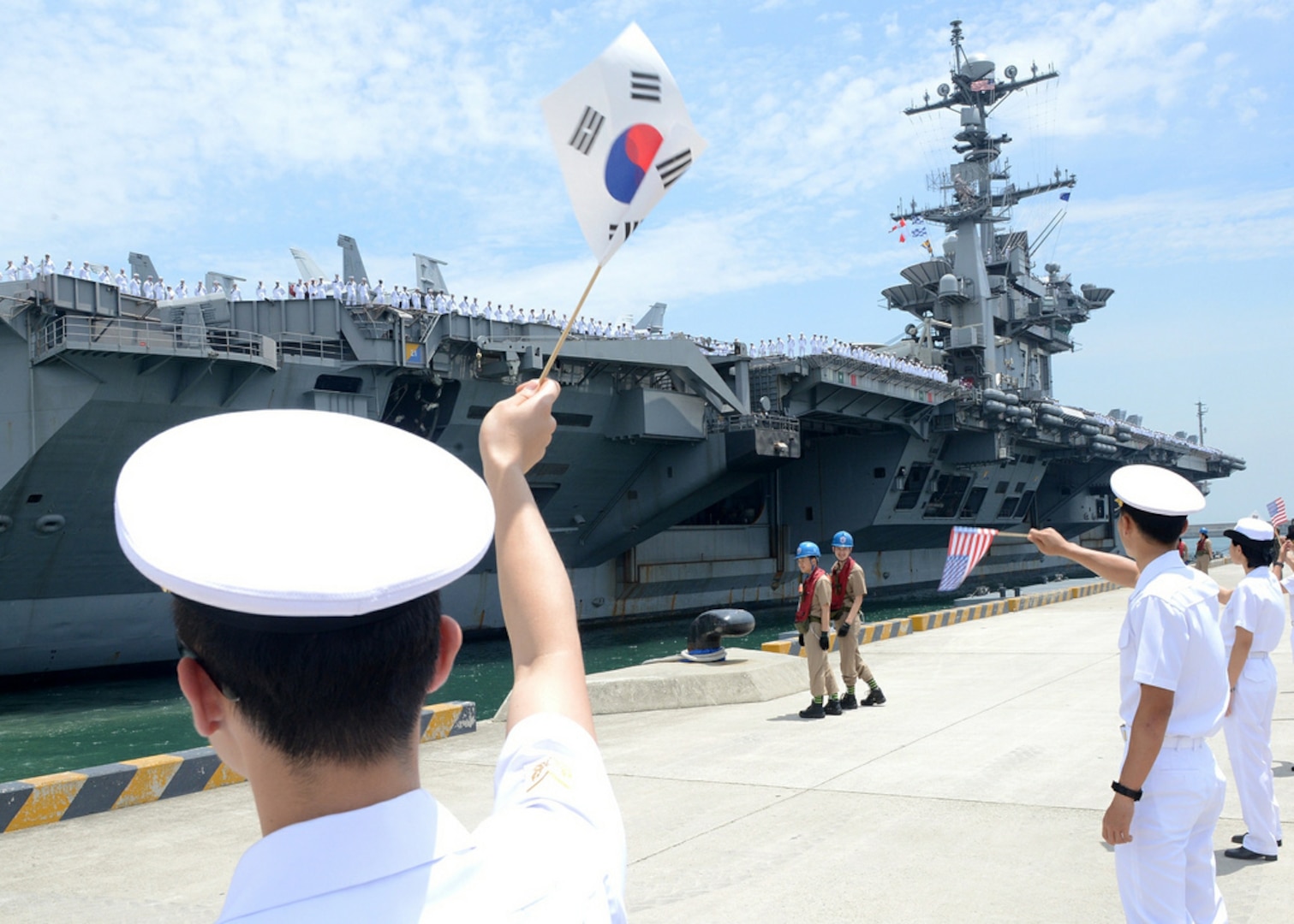BUSAN, Republic of Korea (July 11, 2014) - Republic of Korea Navy sailors wave South Korean and American flags as the aircraft carrier USS George Washington (CVN 73) arrives in Busan for a port visit. George Washington is forward deployed to Yokosuka, Japan, in the U.S. 7th Fleet area of responsibility supporting regional security and stability in the Indo-Asia Pacific. 