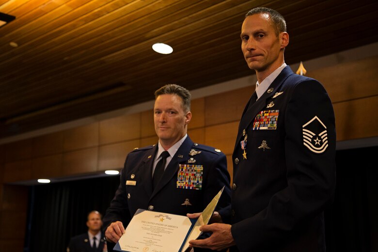 Master Sgt. Roger Sparks (right), and Maj. Joseph Conroy, both with the 212th Rescue Squadron, Alaska Air National Guard, hold an award citation during a ceremony on Joint Base Elmendorf-Richardson, July 11. Sparks was awarded the Silver Star, the nation’s third-highest award for valor, for his role in a firefight with insurgents during Operation Bulldog Bite in Afghanistan’s Watapur Valley on Nov. 14, 2010. His actions during the combat operation resulted in four American lives being saved and four casualties being returned to their families with honor and dignity. (U.S. Army National Guard photo by Sgt. Edward Eagerton/released)