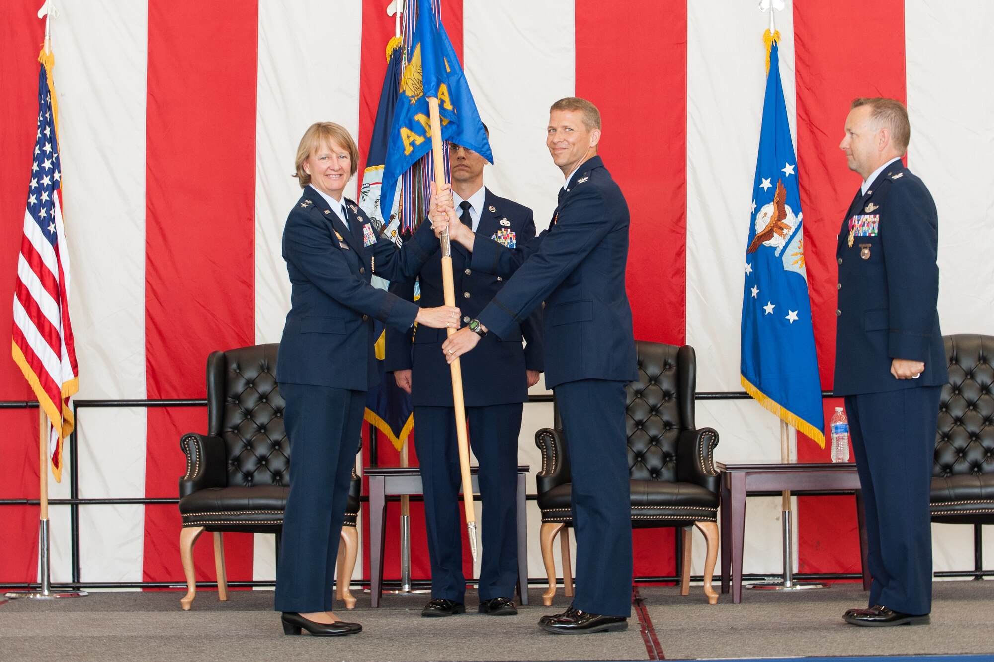 Maj. Gen. Barbara Faulkenberry, 18th Air Force vice commander and presiding officer, passes the 305th Air Mobility Wing guidon to the incoming commander, Col. John F. Price Jr., during the 305th AMW change of command ceremony July 11, 2014,  at Joint Base McGuire-Dix-Lakehurst, N.J. Price served as vice commander of the 375th Air Mobility Wing at Scott Air Force Base, Ill., prior to his assignment with the “Can Do” wing.  (U.S. Air Force photo by Russell Messeroll/Released)