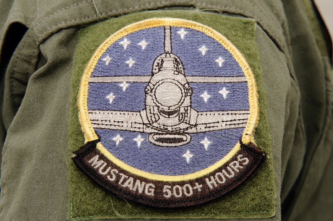 A P-51 Mustang patch designating more than 500 hours of flight time graces the shoulder of Larry Lumpkin’s flight suit. It takes a pilot 200 hours of flight time in the Mustang’s cockpit in order to finally solo the plane without the guidance of an instructor.  (U.S. Air Force photo by Josh Plueger/Released)