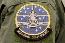 A P-51 Mustang patch designating more than 500 hours of flight time graces the shoulder of Larry Lumpkin’s flight suit. It takes a pilot 200 hours of flight time in the Mustang’s cockpit in order to finally solo the plane without the guidance of an instructor.  (U.S. Air Force photo by Josh Plueger/Released)