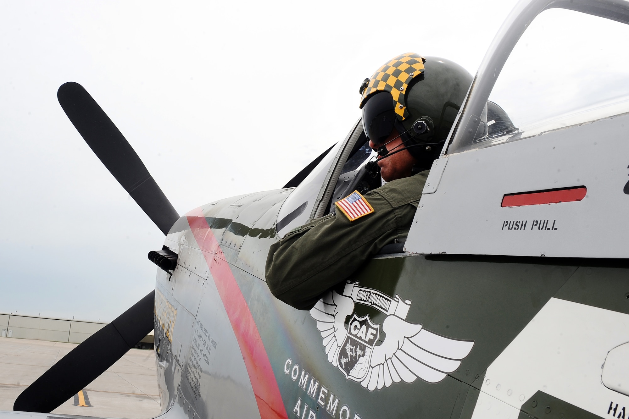 Larry Lumpkin, pilot of the P-51 Mustang, dons his helmet and flight suit for a media photo shoot at the Council Bluffs Municipal Airport, Iowa, on June 27.  The municipal airport is home to one of the many Commemorative Air Force hangars across the country that house vintage aircraft.  (U.S. Air Force photo by Josh Plueger/Released)