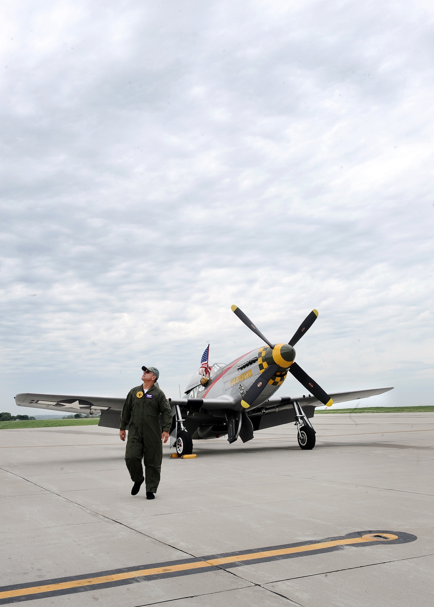 Larry Lumpkin, a P-51 Mustang pilot, keeps an eye on the changing weather overhead as he walks away from the aircraft he just rolled out of the hangar at the Council Bluffs Municipal Airport, Iowa, on June 27. Lumpkin has been the pilot of the P-51 for the past eight Defenders of Freedom Open House and Air Shows at Offutt.  (U.S. Air Force photo by Josh Plueger/Released)