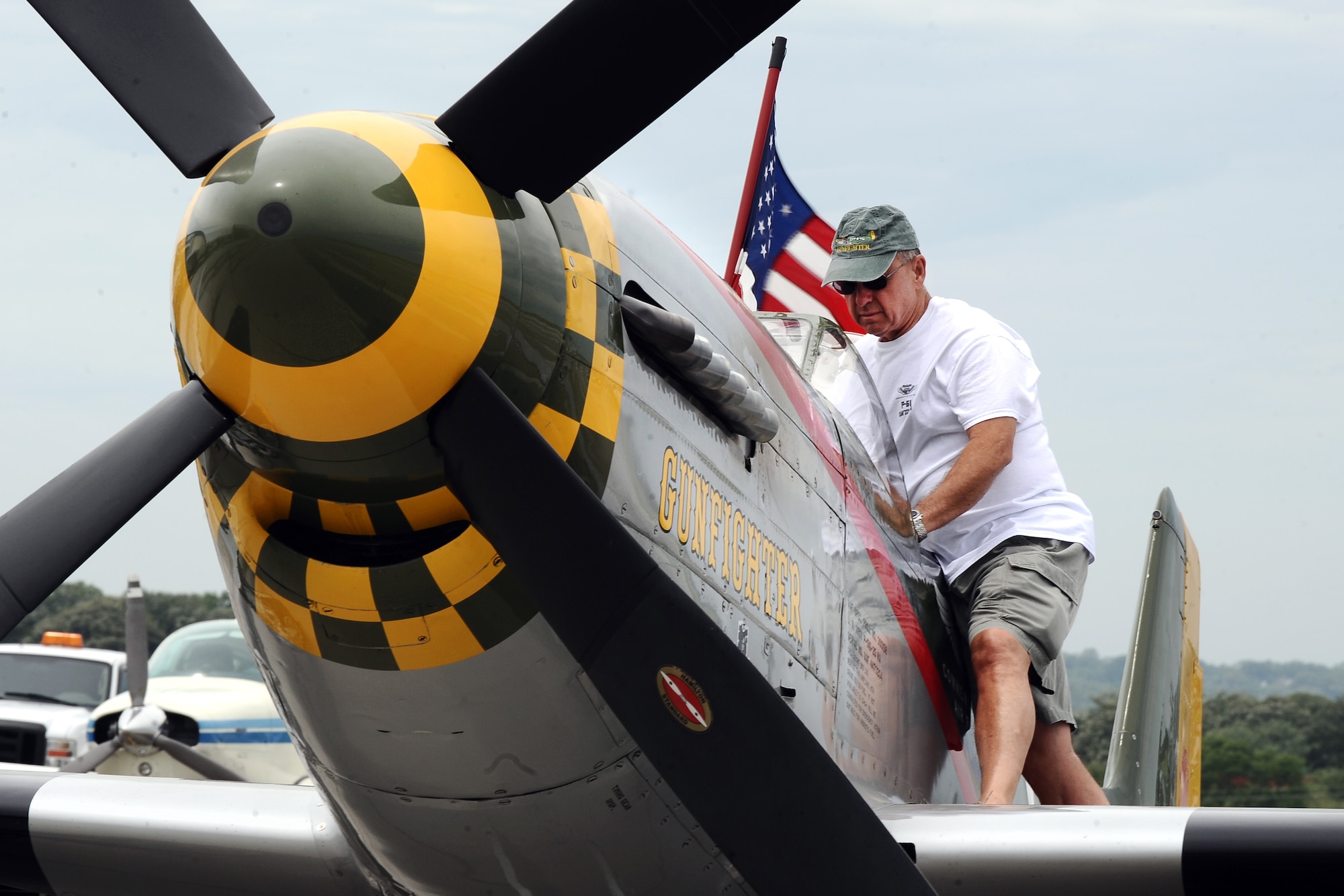 Larry Lumpkin, P-51 Gunfighter Mustang pilot, props up the American flag as he prepares the plane for a media photo shoot at the Council Bluffs Municipal Airport, Iowa on June 27. A commercial pilot for United Airlines, Lumpkin spends his free time chasing a Tora 101 replica Zero at air shows across the nation.  (U.S. Air Force photo by Josh Plueger/Released)