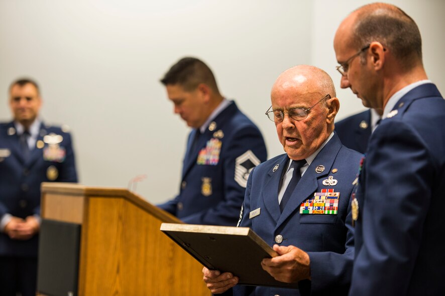 U.S. Air Force retired Chief Master Sgt. Earl Hendrix presents Lt. Col. Peter Dominicis with a gift during his retirement, June 27, 2014 at Moody Air Force Base, Ga. Hendrix read a poem, thanked Dominicis for dedicating 22 years to the Air Force and wished him well. (U.S. Air Force photo by Andrea Jenkins/Released)