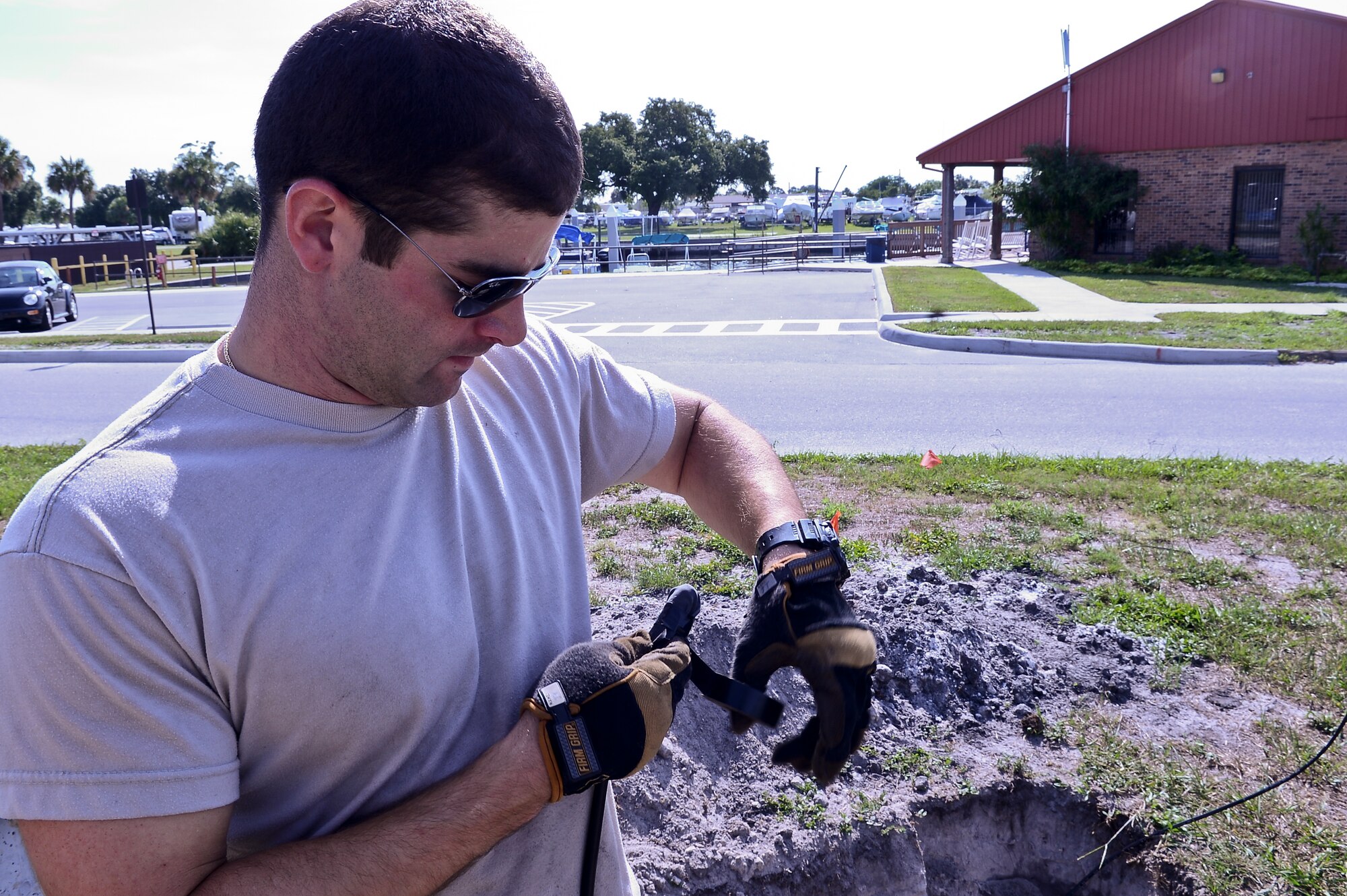 Senior Airman Joe Tartaglia, 6th Communications Squadron cable and antenna systems maintainer, wraps tape around wire at MacDill Air Force Base, Fla., July 11, 2014. Tartaglia and the other cable dogs, as they refer to themselves, laid the wire to install an emergency beach phone near the Marina. (U.S. Air Force photo by Senior Airman Vernon L. Fowler Jr./Released)
