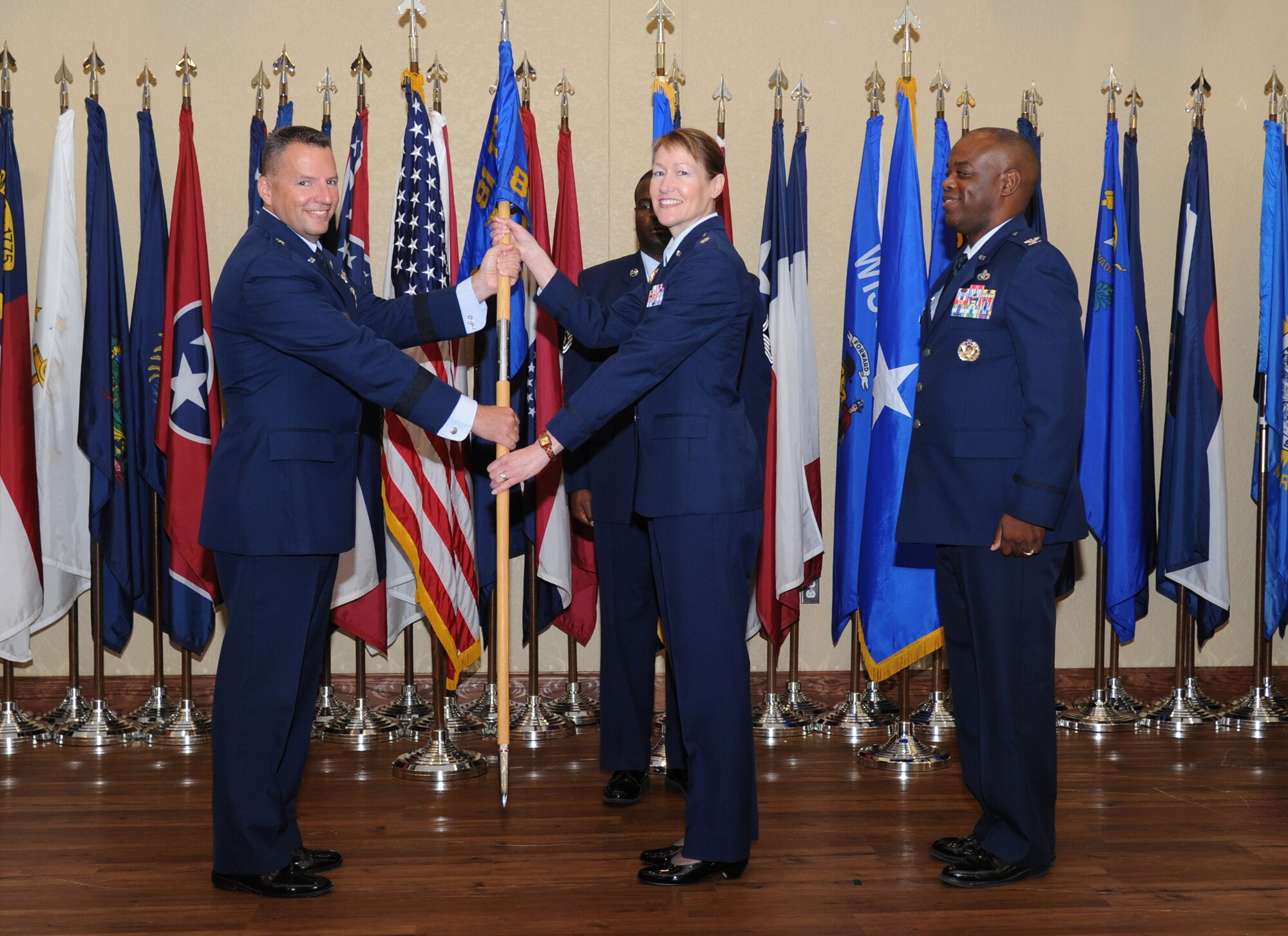 Brig. Gen. Patrick Higby, 81st Training Wing commander, passes the guideon to Lt. Col. Susan Airola-Skully, incoming 81st Mission Support Group commander, as Col. Mark Vivians, outgoing commander, stands by during the 81st MSG change of command ceremony July 10, 2014, at the Bay Breeze Event Center, Keesler Air Force Base, Miss. Airola-Skully was previously the deputy director, officer and enlisted personnel management, for the Under Secretary of Defense for Personnel and Readiness, Office of the Secretary of Defense, at the Pentagon.  Vivians will retire July 11.  (U.S. Air Force photo by Kemberly Groue)