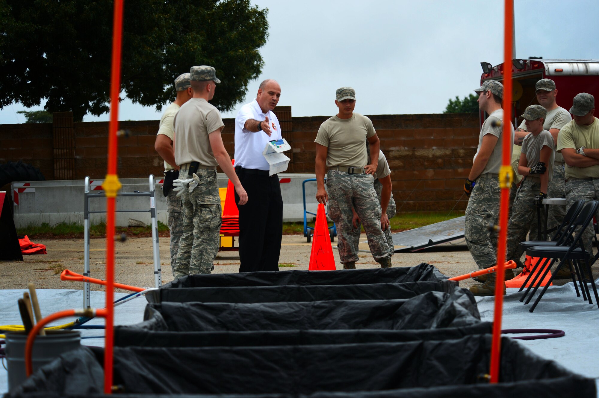 The 20th Civil Engineer Squadron fire chief explains the steps of the hazardous material decontamination process at Shaw Air Force Base, S.C., July 11, 2014. During the two day training, the 20th CES firefighters spent several hours receiving their annual training becoming equipped with the skills needed to properly decontaminate personnel. (U.S. Air Force photo by Airman 1st Class Jensen Stidham/Released)