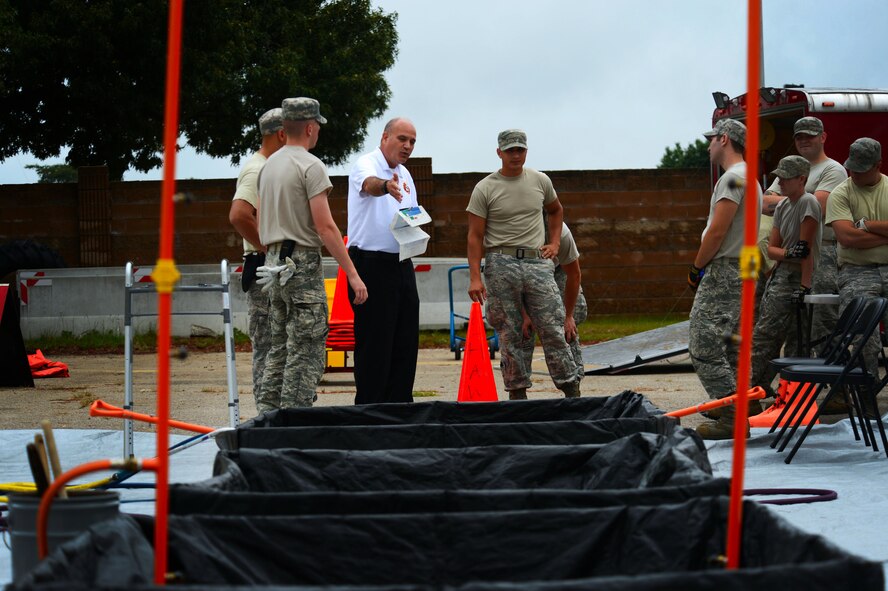 The 20th Civil Engineer Squadron fire chief explains the steps of the hazardous material decontamination process at Shaw Air Force Base, S.C., July 11, 2014. During the two day training, the 20th CES firefighters spent several hours receiving their annual training becoming equipped with the skills needed to properly decontaminate personnel. (U.S. Air Force photo by Airman 1st Class Jensen Stidham/Released)