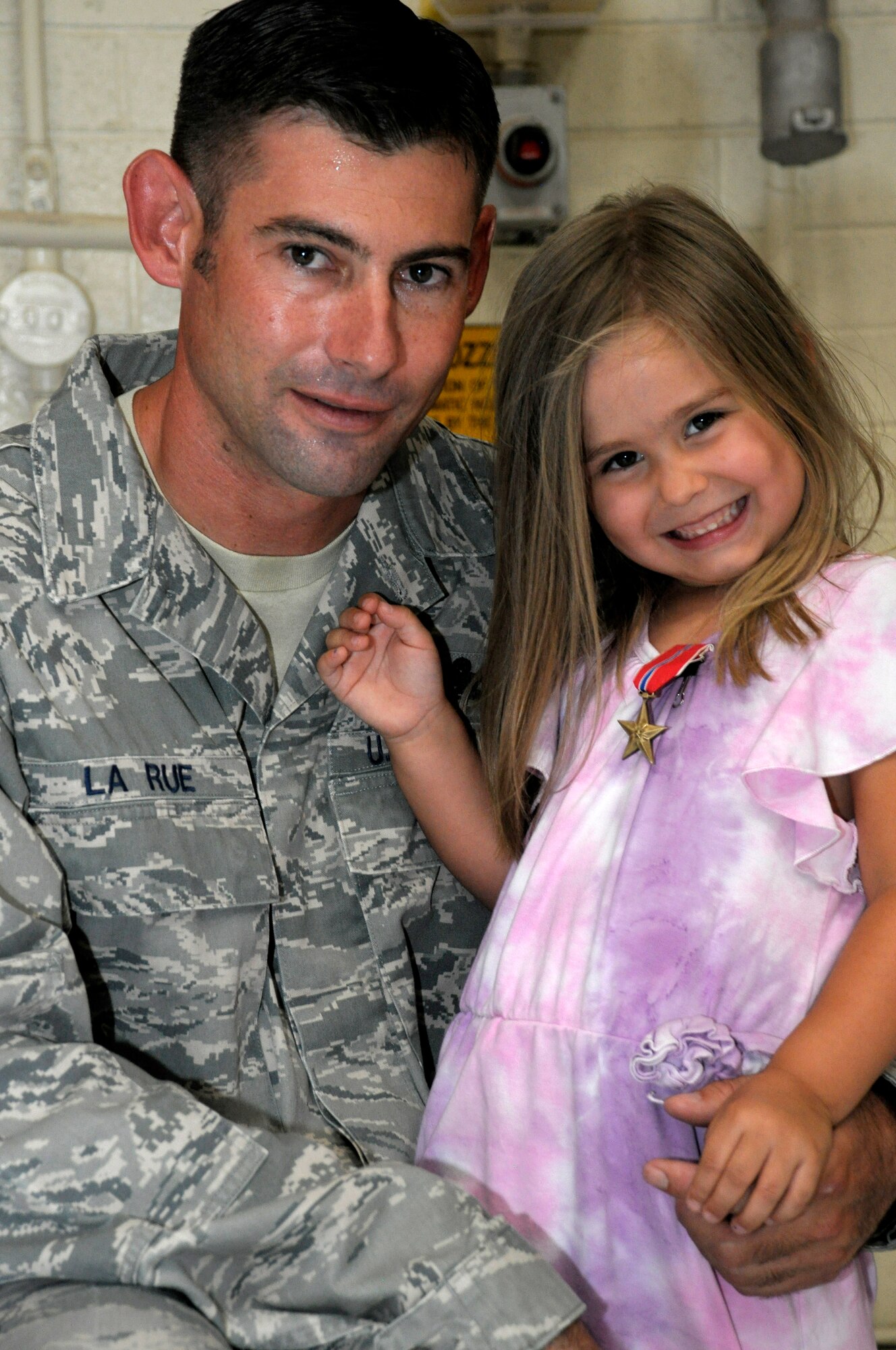 Master Sgt. Nathan La Rue, 56th Equipment Maintenance Squadron munitions conventional maintenance NCO in charge, poses with his daughter, Hailey Brianne La Rue, 4, after pinning his Bronze Star Medal on her for “safe keeping.” La Rue’s actions during his Afghanistan deployment earned him the medal which was presented June 18 at Luke Air Force Base. (U.S. Air Force photo/Staff Sgt. Timothy Boyer)