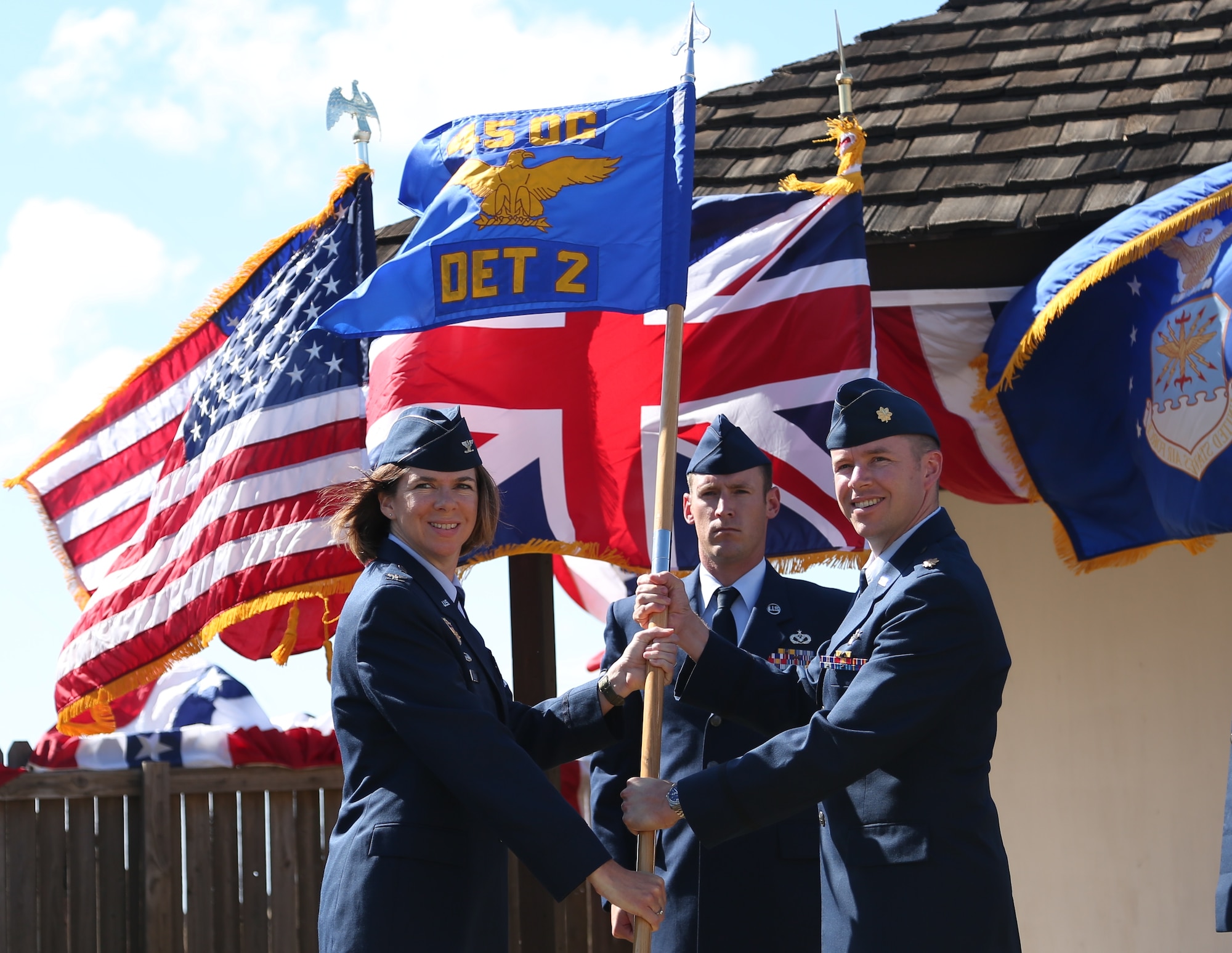Col. Shannon Klug, 45th Weather Squadron commander and acting Operations Group Deputy Commander, left, presents Maj. Andrew Emslie, 45th Operations Group Detachment 2 commander, with the 45th OG Det. 2 guidon during a Change of Command ceremony July 8, 2014, at Ascension Auxiliary Airfield, Ascension Island, South Atlantic. Changes of Command are a military tradition representing the transfer of responsibilities from the presiding officials to the upcoming official. (U.S. Air Force photo/Herbert Orlandi)