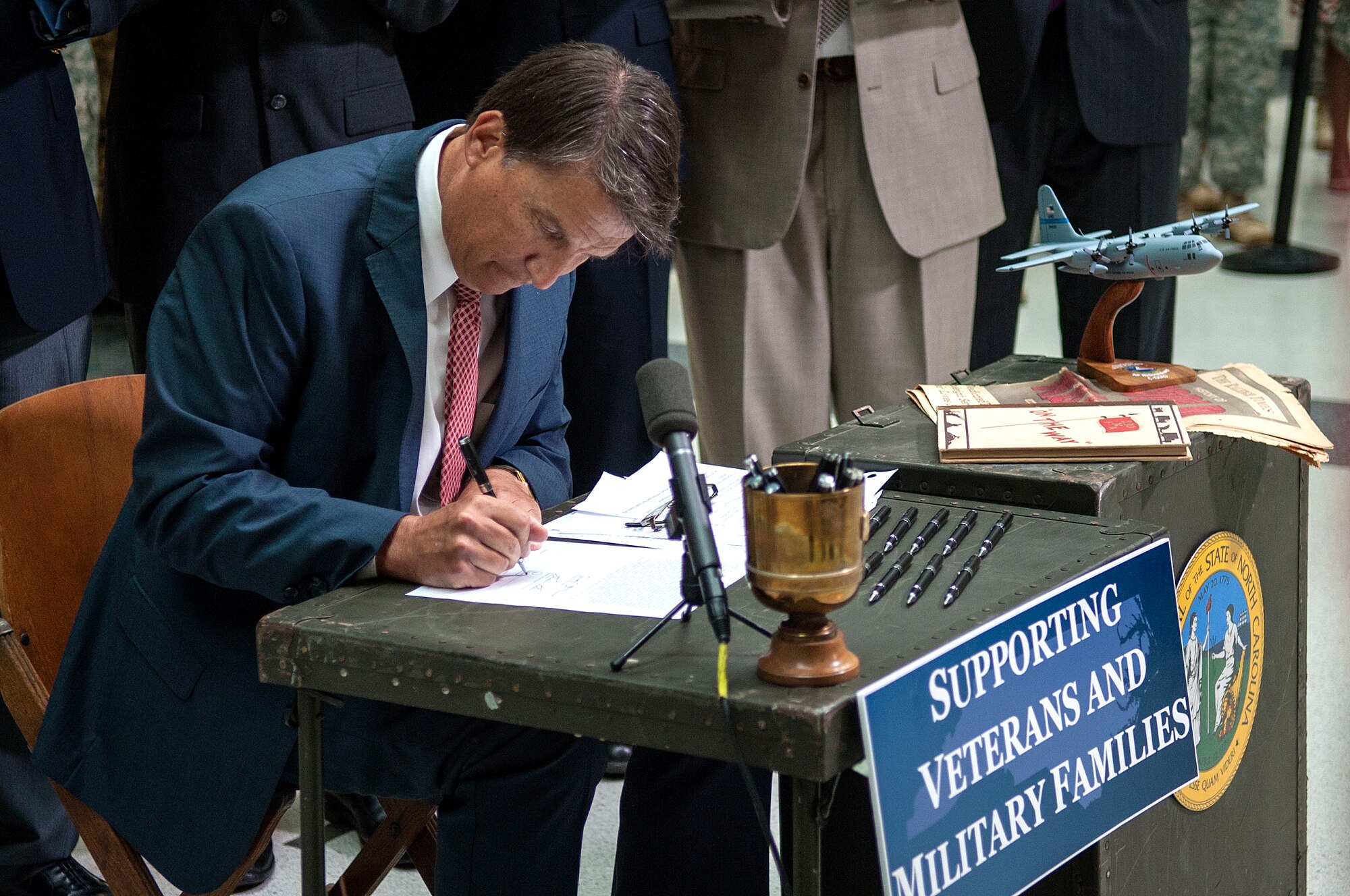 North Carolina Governor Pat McCory signs Senate Bill 761, July 10, 2014, in Raleigh, North Carolina. McCrory signed legislature that will ensure college credits are given to students who have already completed similar training through the military. Five Airmen were selected from Seymour Johnson Air Force Base, North Carolina to attend the signing.  (U.S. Air Force photo/Airman 1st Class Shawna L. Keyes) 