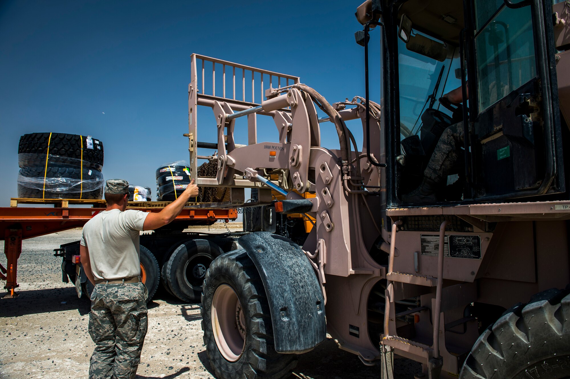 U.S. Air Force Staff Sgt. Jordan Bly, 386th Expeditionary Logistics Readiness Squadron transportation management office inbound cargo NCO in charge, assists Senior Airman Anthony Streifel, 386th ELRS traffic management specialist, as he unloads cargo with a forklift May 31, 2014 at an undisclosed location in Southwest Asia. Bly deployed here from the 18th LRS, Kadena Air Base, Japan, while Streifel deployed from the 354th LRS, Eielson Air Force Base, Alaska, both in support of Operation Enduring Freedom. (U.S. Air Force photo by Staff Sgt. Jeremy Bowcock)