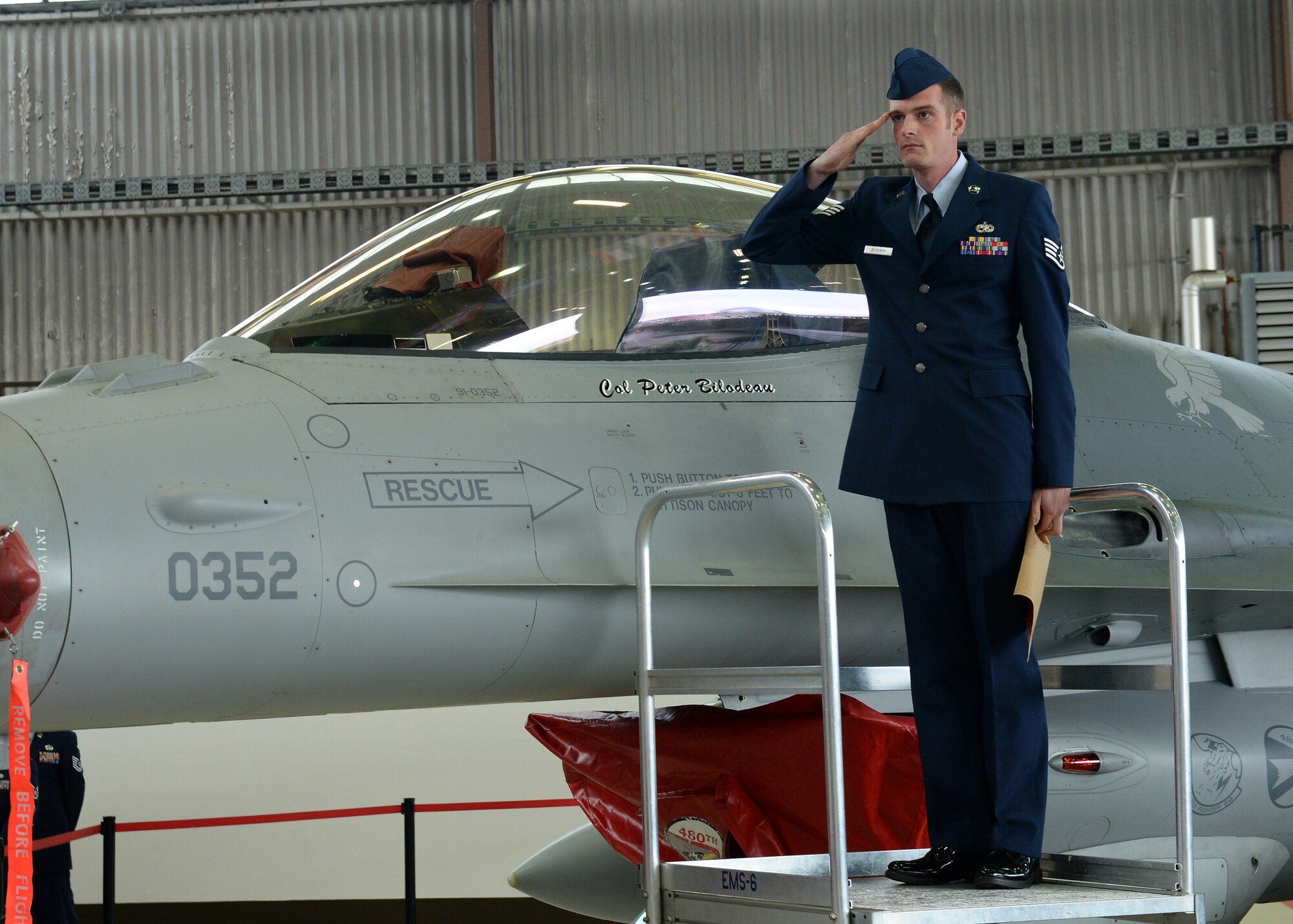 U.S. Air Force Staff Sgt. Bradley Buckner, 52nd Aircraft Maintenance Squadron dedicated crew chief, salutes U.S. Air Force Col. Peter Bilodeau, 52nd Fighter Wing commander, after unveiling Bilodeau’s name on the wing’s flagship F-16 Fighting Falcon fighter aircraft. Bilodeau assumed command of the wing after having served as the 8th Operations Group commander at Kunsan Air Base, Republic of Korea. (U.S. Air Force photo by Staff Sgt. Daryl Knee/Released)