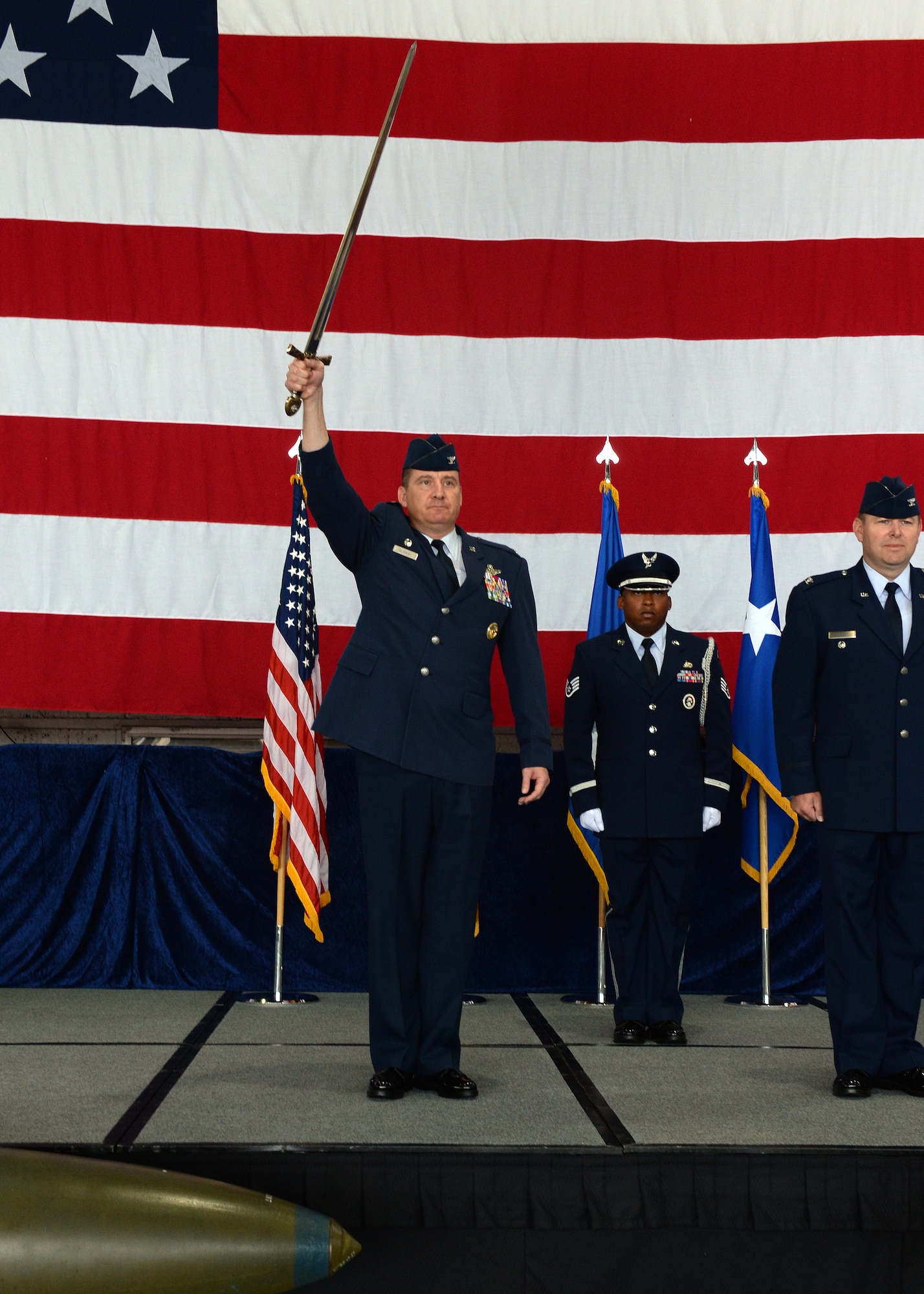 U.S. Air Force Col. Peter Bilodeau, 52nd Fighter Wing commander, raises a ceremonial saber during an assumption of command ceremony July 11, 2014, in Hangar 1 at Spangdahlem Air Base, Germany. U.S. Air Force Col. Lars Hubert, 52nd FW vice commander, presented the saber to Bilodeau in this tradition that dates back to the 1980s. (U.S. Air Force photo by Staff Sgt. Daryl Knee/Released)
