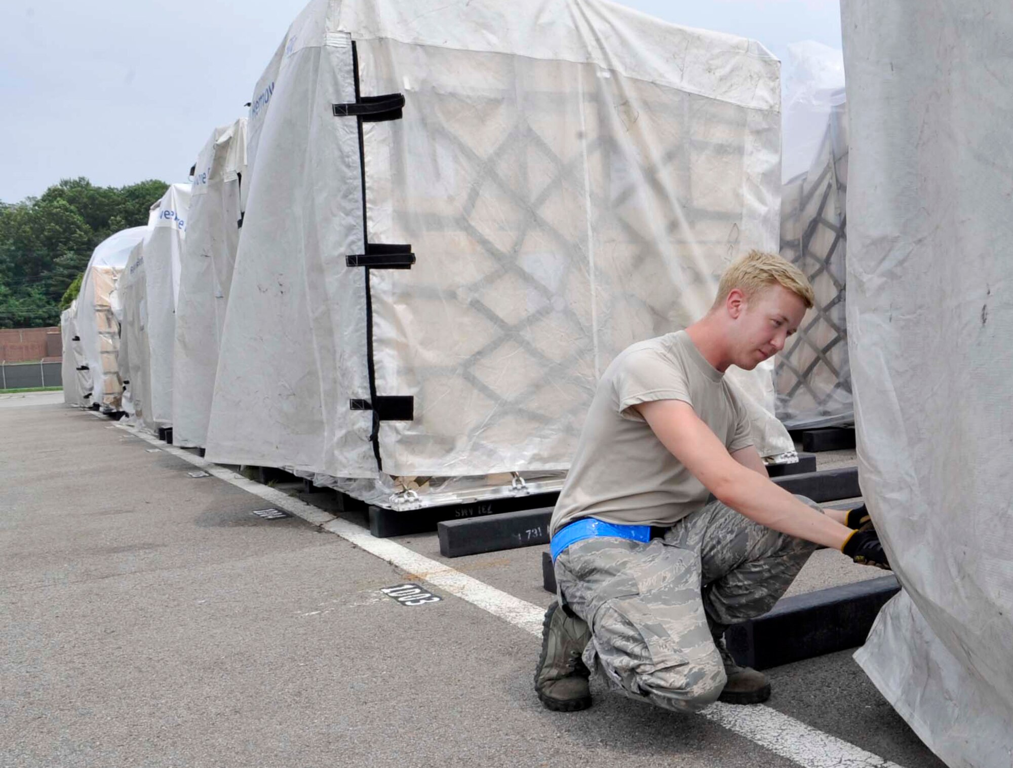 Airman 1st Class Steven Tiell, 731st Air Mobility Squadron aircraft services technician, inspects a pallet at Osan Air Base, Republic of Korea, July 10, 2014. The reusable pallet covers have been 100 percent effective and reduced water damage to zero. (U.S. Air Force photo/Senior Airman Matthew Lancaster)