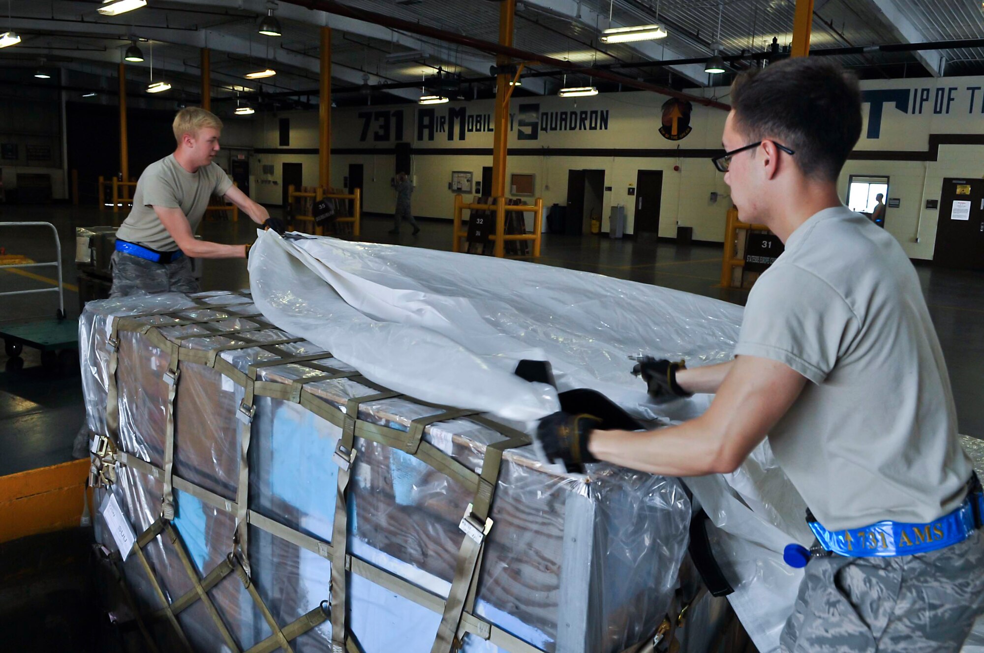 Airman 1st Class Steven Tiell and Airman 1st Class Joseph Shank, 731st Air Mobility Squadron aircraft services technicians, put a reusable pallet cover onto a pallet at Osan Air Base, Republic of Korea, July 10, 2014. The 731st AMS processed 5,800 pallets in 2012, 5,084 pallets in 2013 and are on track for approximately 6,000 pallets for 2014. (U.S. Air Force photo/Senior Airman Matthew Lancaster)