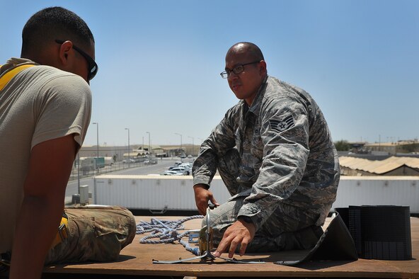Staff Sgt. Pierre Convers, a 380th Air Expeditionary Wing ground safety craftsman, discusses proper safety techniques with Airman 1st Class Jordan Yoon, a 577th Expeditionary Prime Beef Squadron water and fuel systems maintainer, July 10, 2014, at an undisclosed location in Southwest Asia. Convers, deployed from Seymour Johnson Air Force Base, N.C., has been recognized as a 380th Air Expeditionary Wing warrior of the week. (U.S. Air Force photo by Tech. Sgt. Russ Scalf/Released)