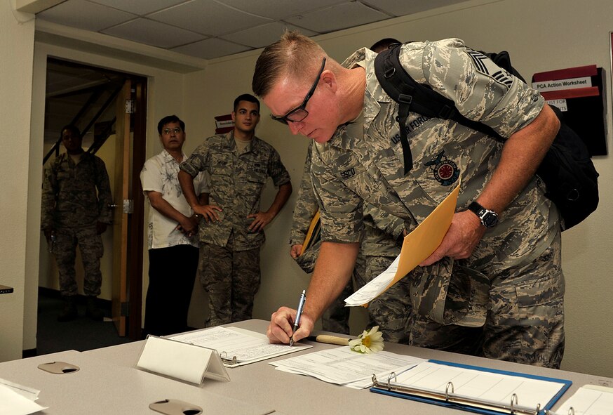U.S. Air Force Chief Master Sgt. Albert Sisco, new 18th Civil Engineer Squadron fire chief, fills out the in-process check list at the military personnel section on Kadena Air Base, Japan, July 11, 2014. The newcomers came from Air Force Bases all over the world. The PCS season's peak is from May to August with Kadena welcoming approximately 2,000 newcomers and parting with approximately 3,000 airmen annually. (U.S. Air Force photo by Naoto Anazawa/Released)