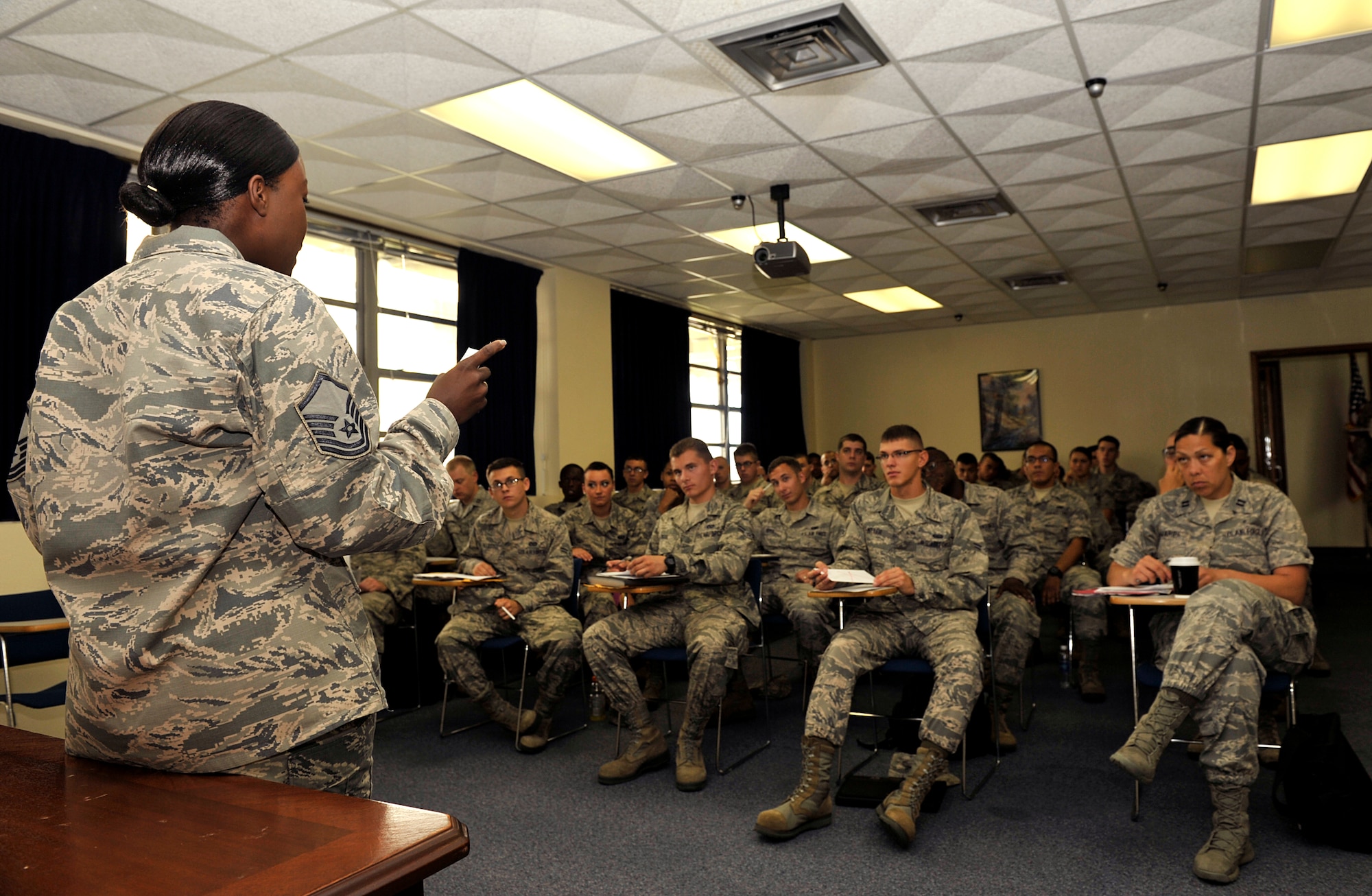 U.S. Air Force Master Sgt. Karla Peters, 18th Force Support Squadron superintendent of customer service, briefs Airmen in-processing on Kadena Air Base, Japan, July 11, 2014. All newcomers must in-process at the military personnel section first prior to attending Base Newcomer's Orientation. They also must visit the 18th Security Forces Squadron Pass and Registration section to get registered in the Defense Biometric Identification System within 72 hours of arrival on station. (U.S. Air Force photo by Naoto Anazawa/Released)