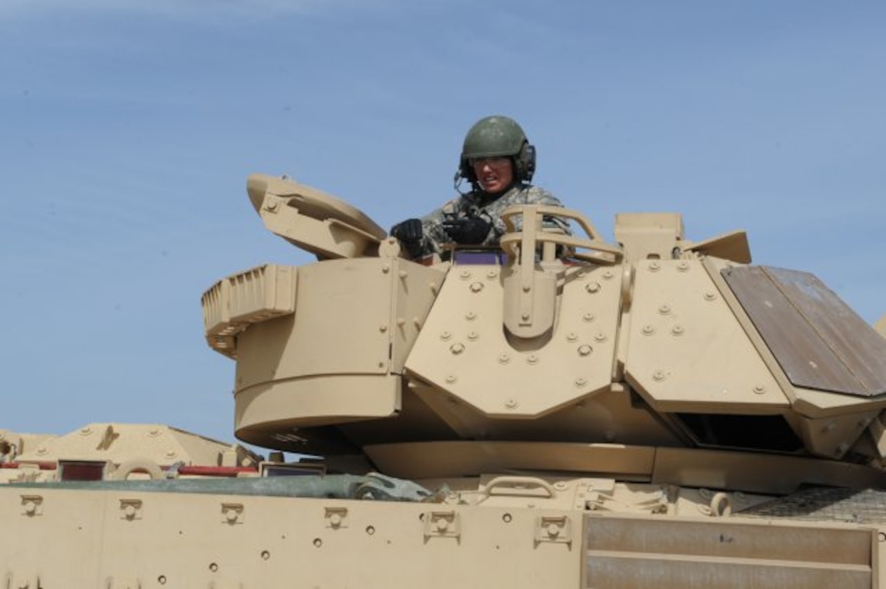 Army Maj. Chrissy Cook sits at the helm of her Bradley fighting vehicle during a media opportunity at Fort Hood, Texas, July 7, 2014. In June, Cook led her crew to her battalion’s "Top Gun" title in a gunnery exercise. U.S. Army photo by Heather Graham-Ashley