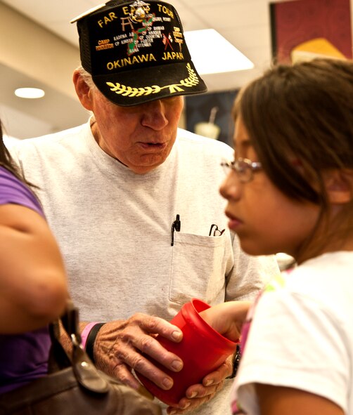 Don Magers, retired Marine, hands out candy to guests at the Whiteman Commissary June 25, 2014. Magers celebrated his 80th birthday this past Independence Day. (U.S. Air Force photo by Senior Airman Daniel Phelps/Released)