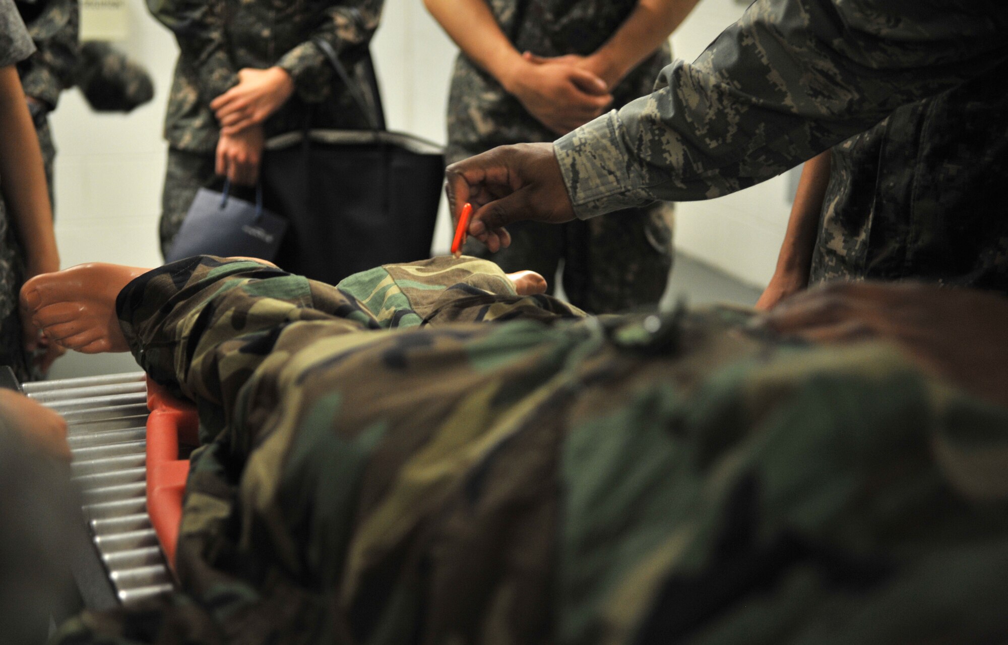 Tech. Sgt. Destin Huey, 51st Aerospace Medicine Squadron optometry technician and night shift alternate decontamination team chief for operational readiness exercises, simulates cutting off a mock chemical attack casualty’s Mission Oriented Protective Posture gear during a tour of the 51st Medical Group at Osan Air Base, Republic of Korea, July 11, 2014. Students from the Republic of Korea Aeromedical Center Primary Flight Nurse Course visited the decontamination area and emergency room after receiving a briefing about the 51st MDG’s mission and capabilities. (U.S. Air Force photo/Airman 1st Class Ashley J. Thum)