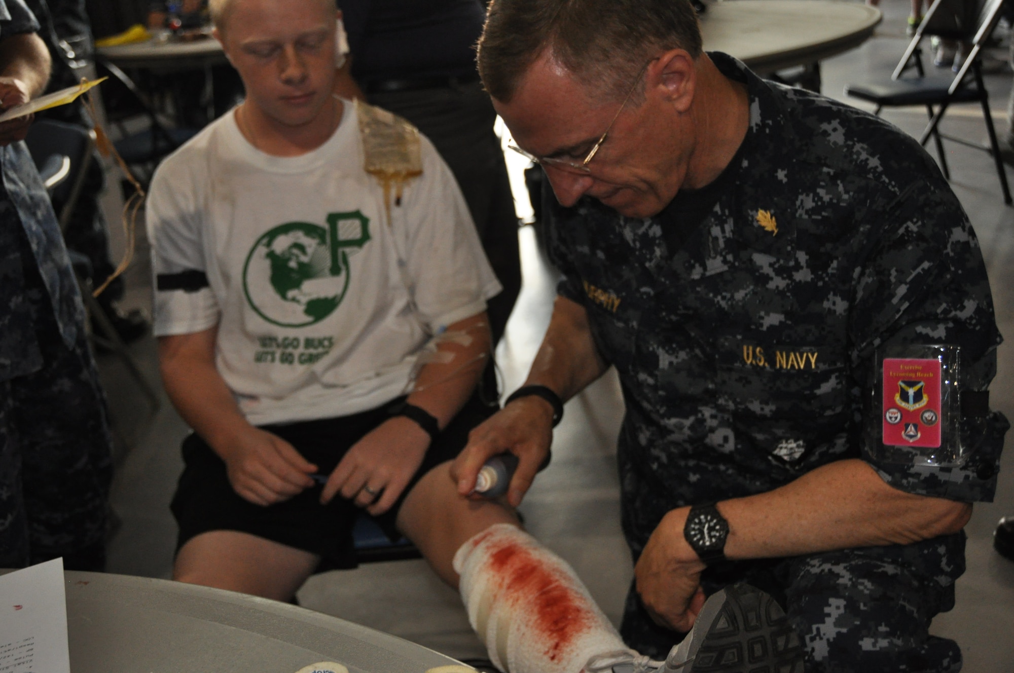 Lt. Cmdr. Tim Murphy, psychologist with the Navy Reserve Medical Service Corps at Walter Reed National Military Medical Center at Bethesda, sprays fake blood on the bandages of a Civil Air Patrol Cadet as part of preparation for a National Disaster Medical System Exercise at the Pittsburgh International Airport Air Reserve Station, July 12, 2014. (U.S. Air Force photo by Senior Airman Marjorie A. Bowlden)