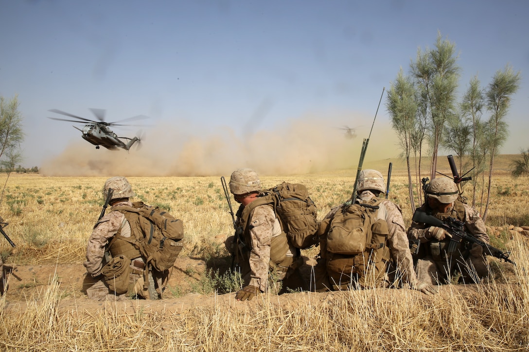 U.S. Marines watch as CH-53E Super Stallion helicopters land in a field during a mission in Helmand province, Afghanistan, July 5, 2014. The Marines are assigned to Bravo Company, 1st Battalion, 7th Marine Regiment.